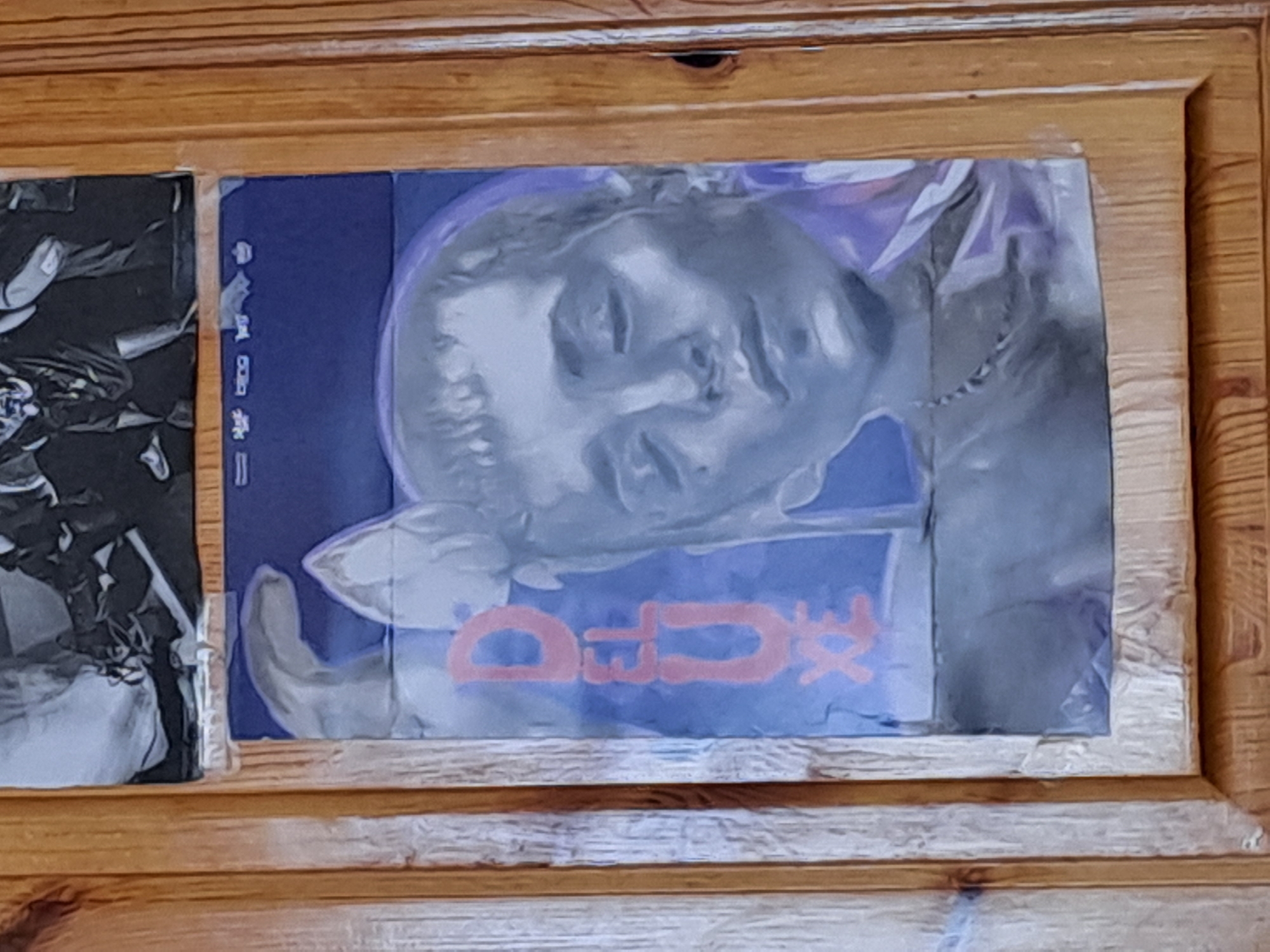 Two posters displayed on wooden surface at unknown location