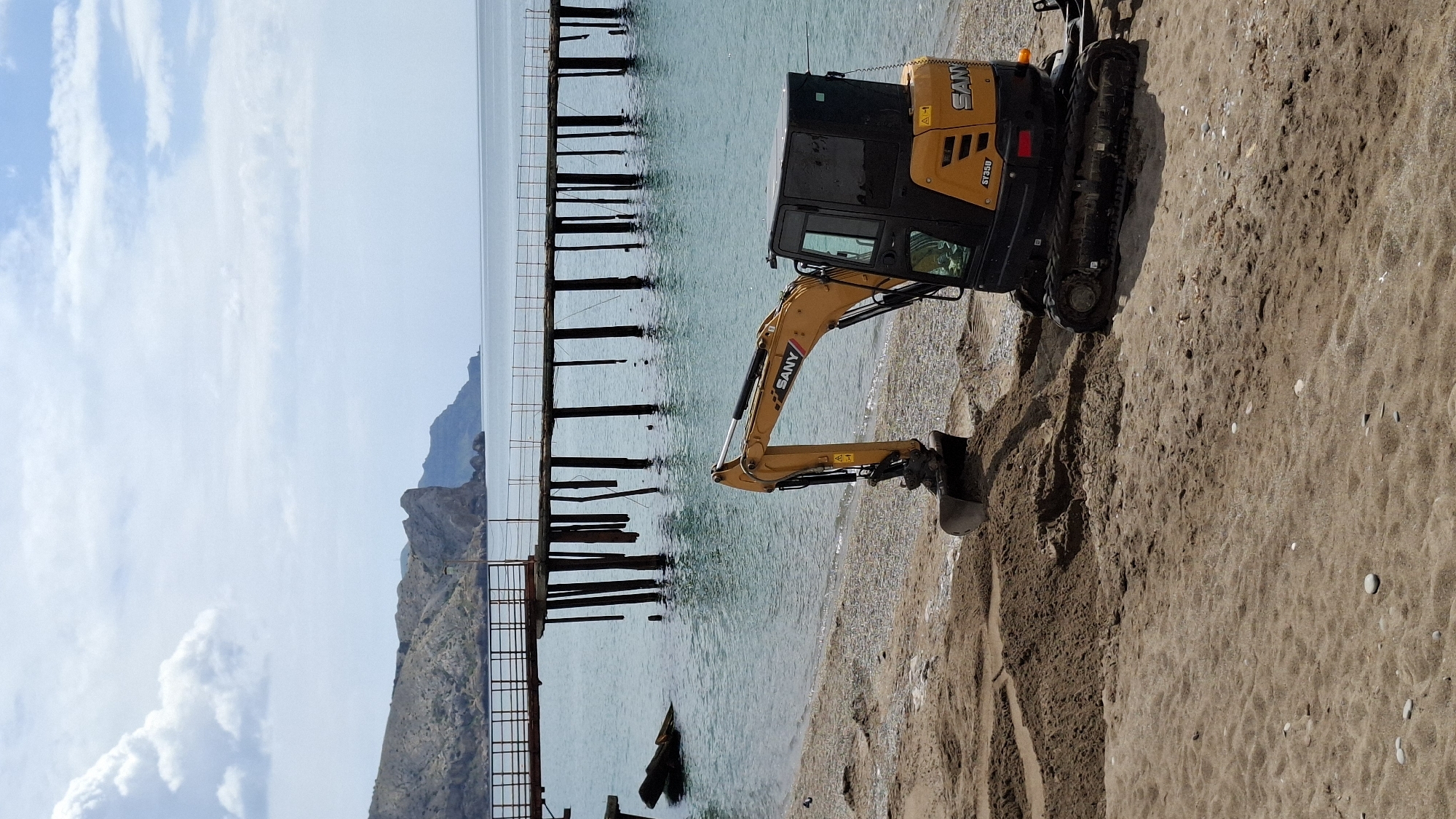 Beach excavation work draws curious onlookers at coastal location