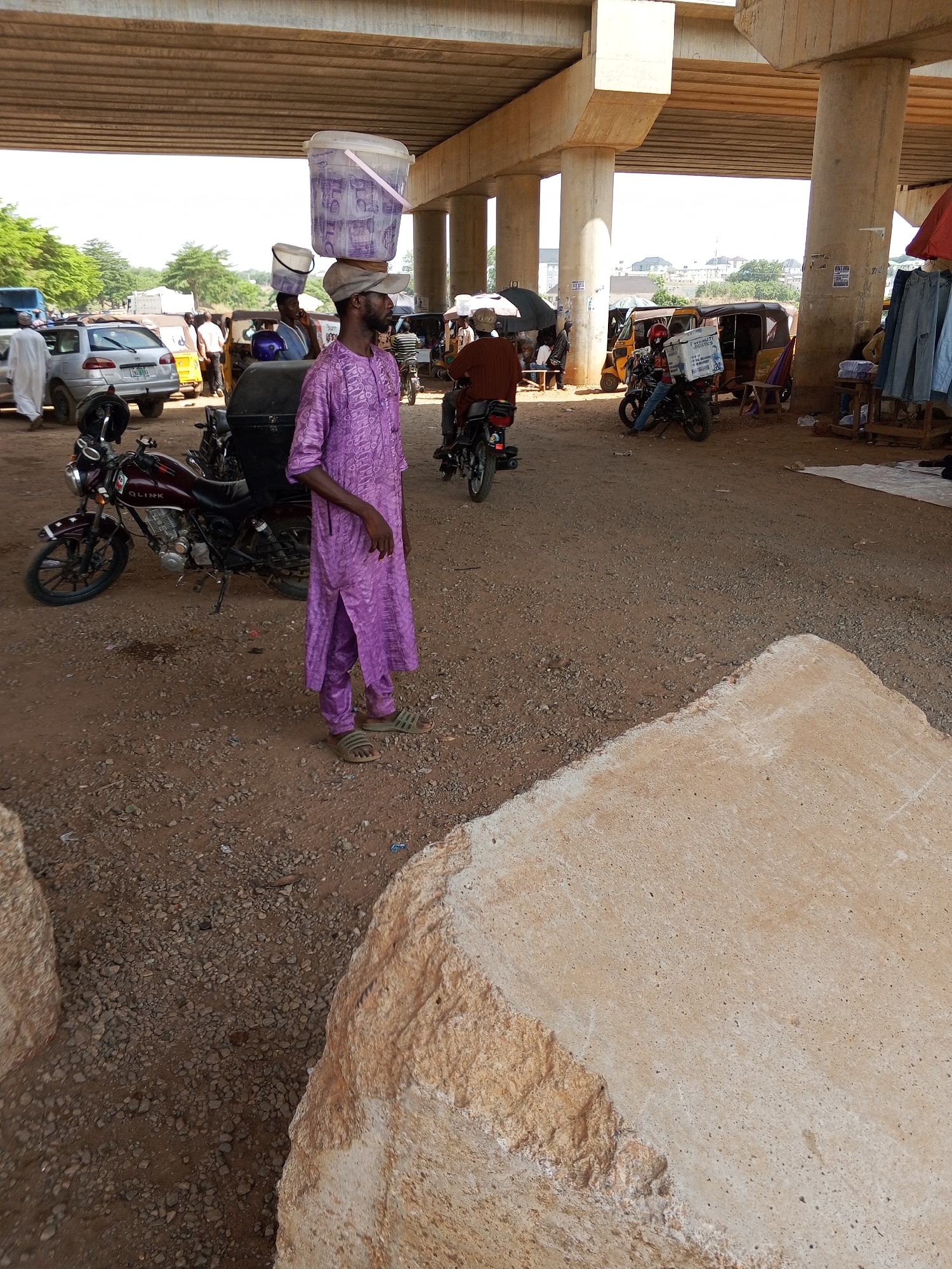 Man carries bucket on head under overpass in Nigerian village