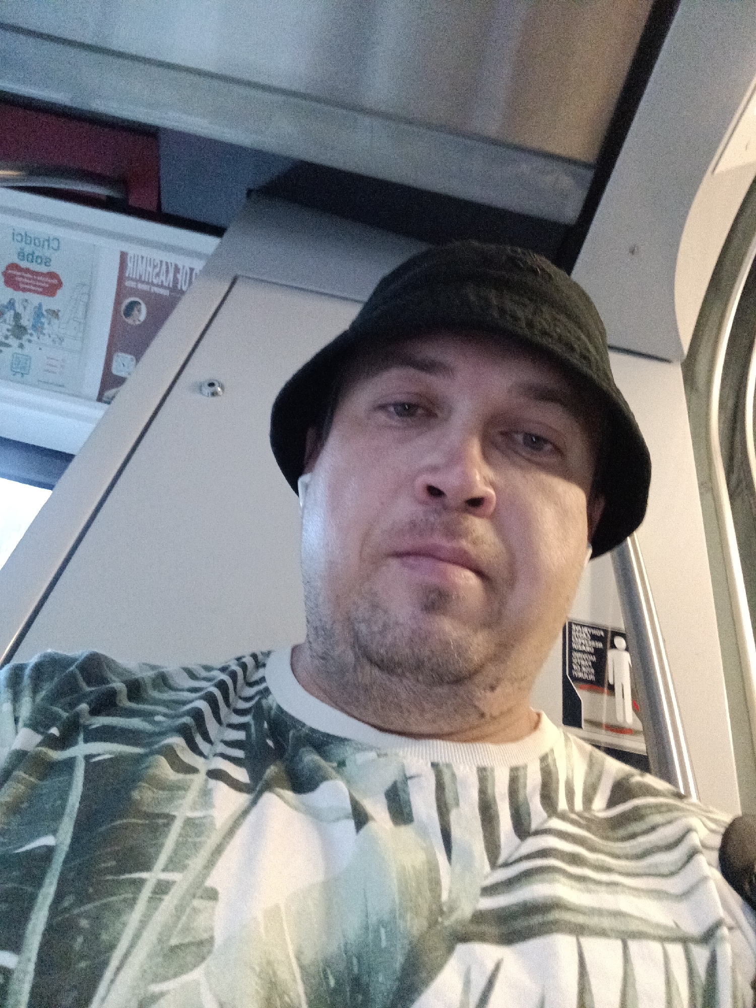 Selfie on a Prague train, bucket hat and tropical tee.