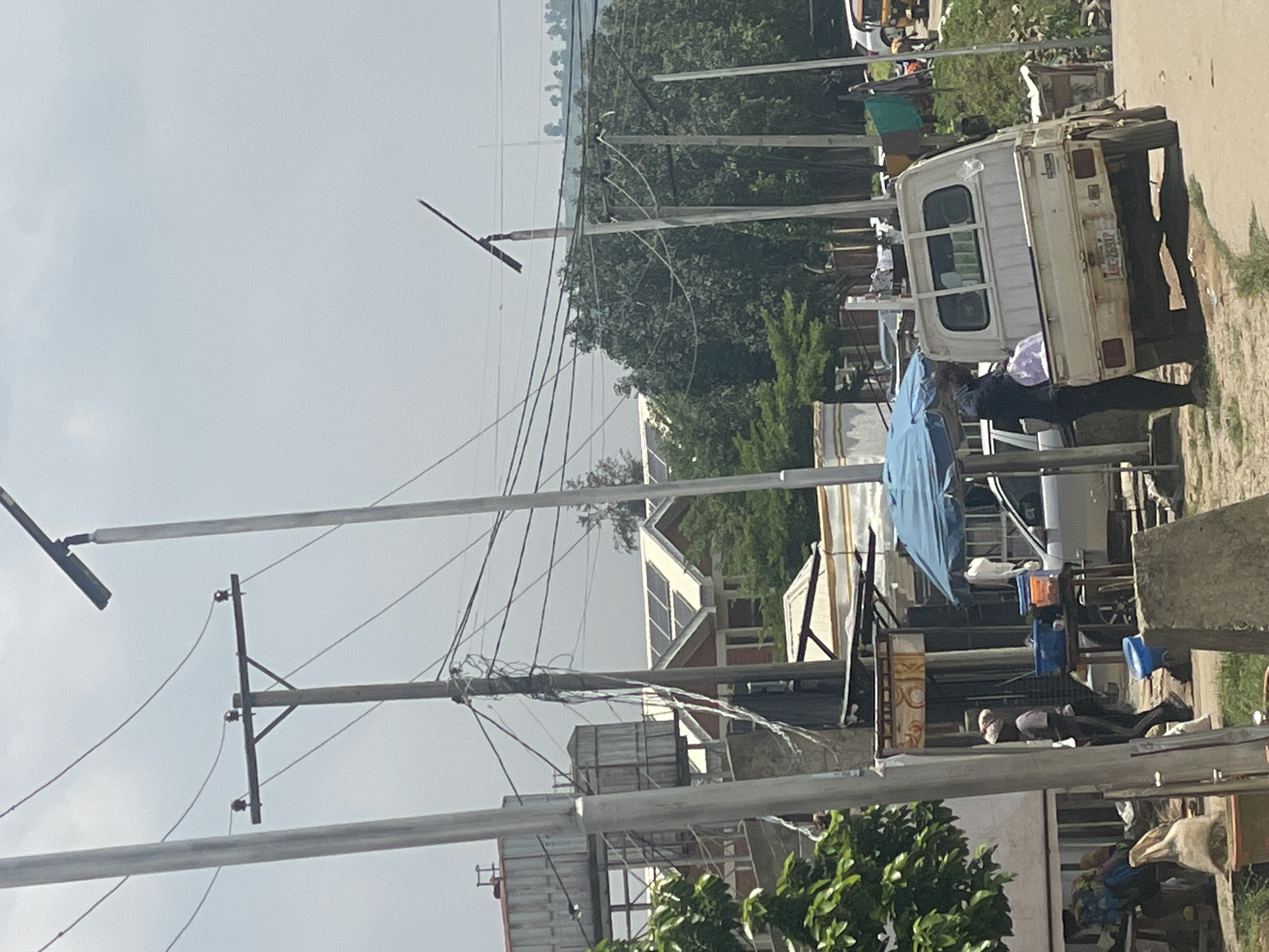 Busy Abuja street with parked vehicles and roadside shops