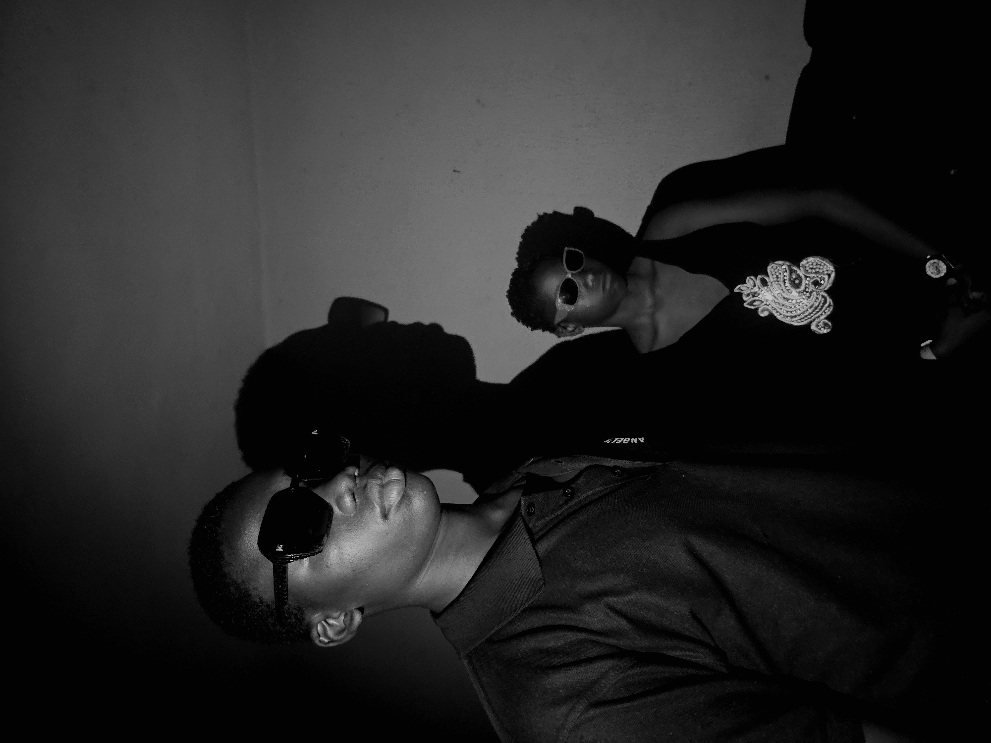 Two people photographed indoors wearing glasses and shirts