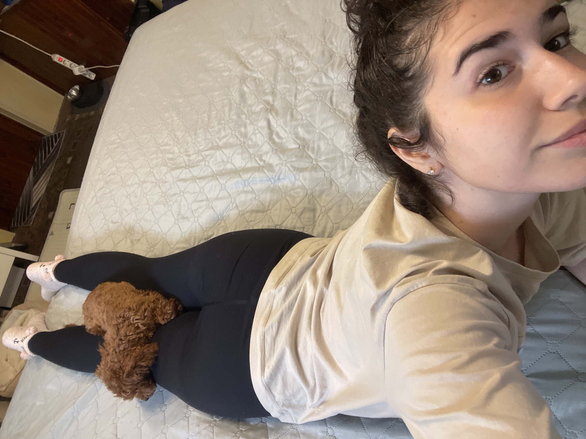Woman rests with poodle on bed in Sofia