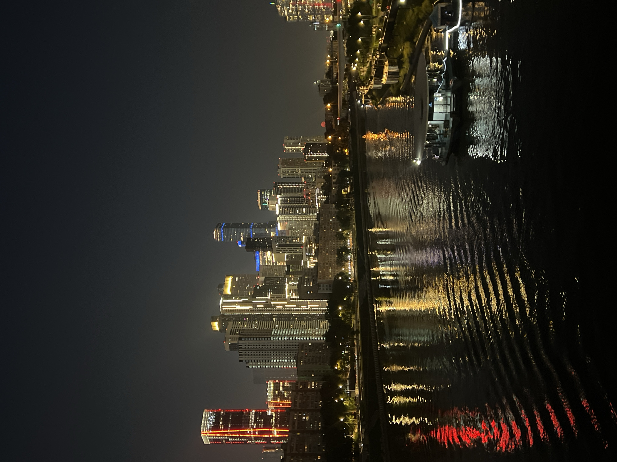 Glittering city skyline reflects across a wide river at night
