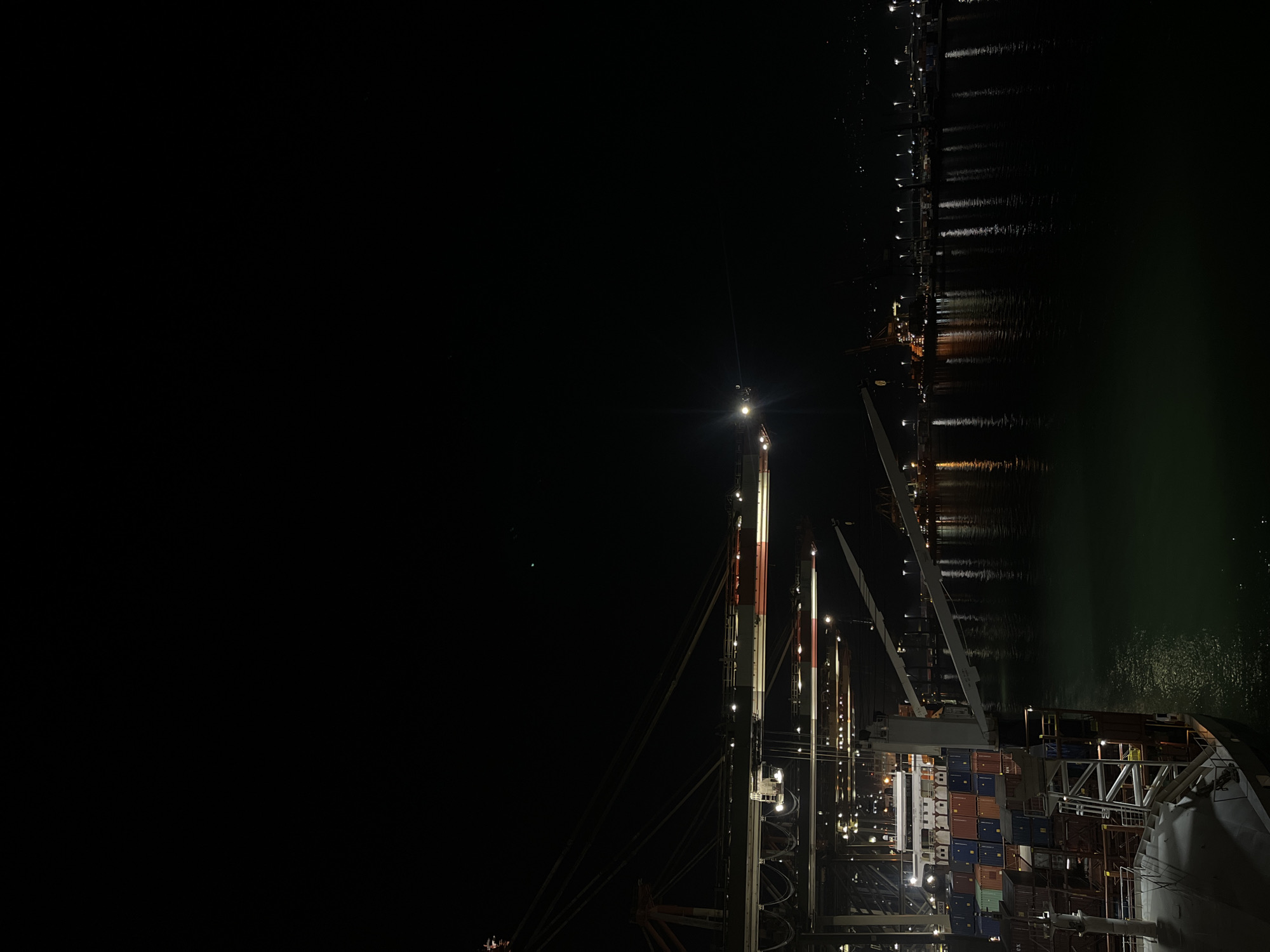 Illuminated cargo ship observed at nighttime port operations