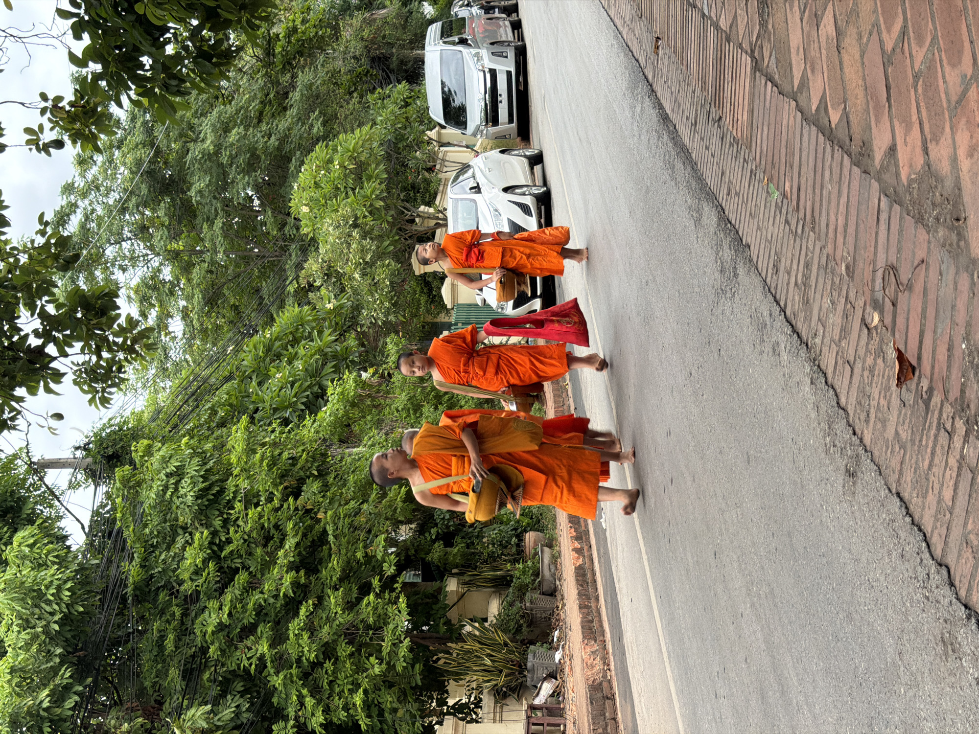 Morning alms procession on rain-slicked streets in Luang Prabang