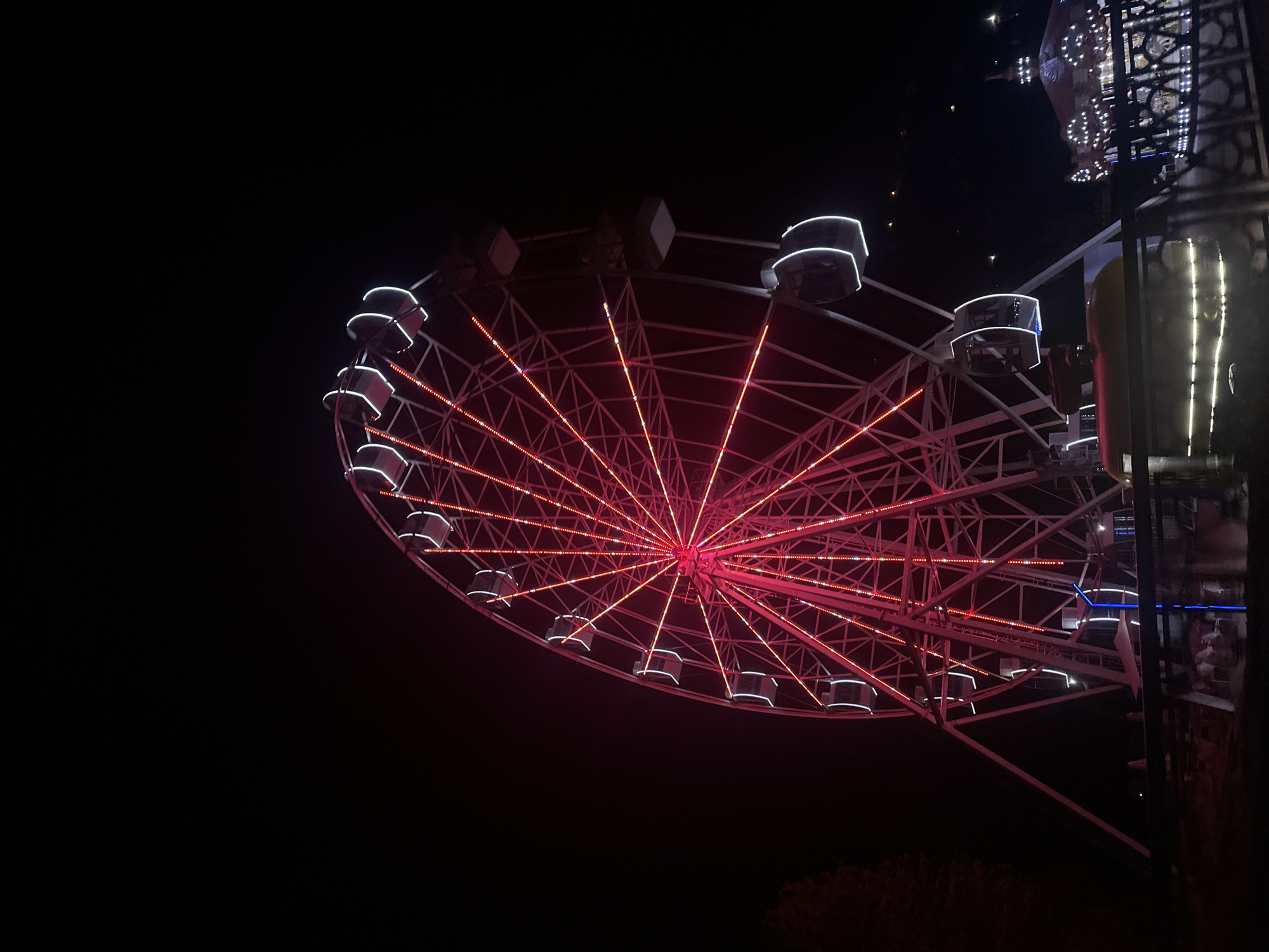 New Athos landmarks, waterfall, and fairground lights at dusk