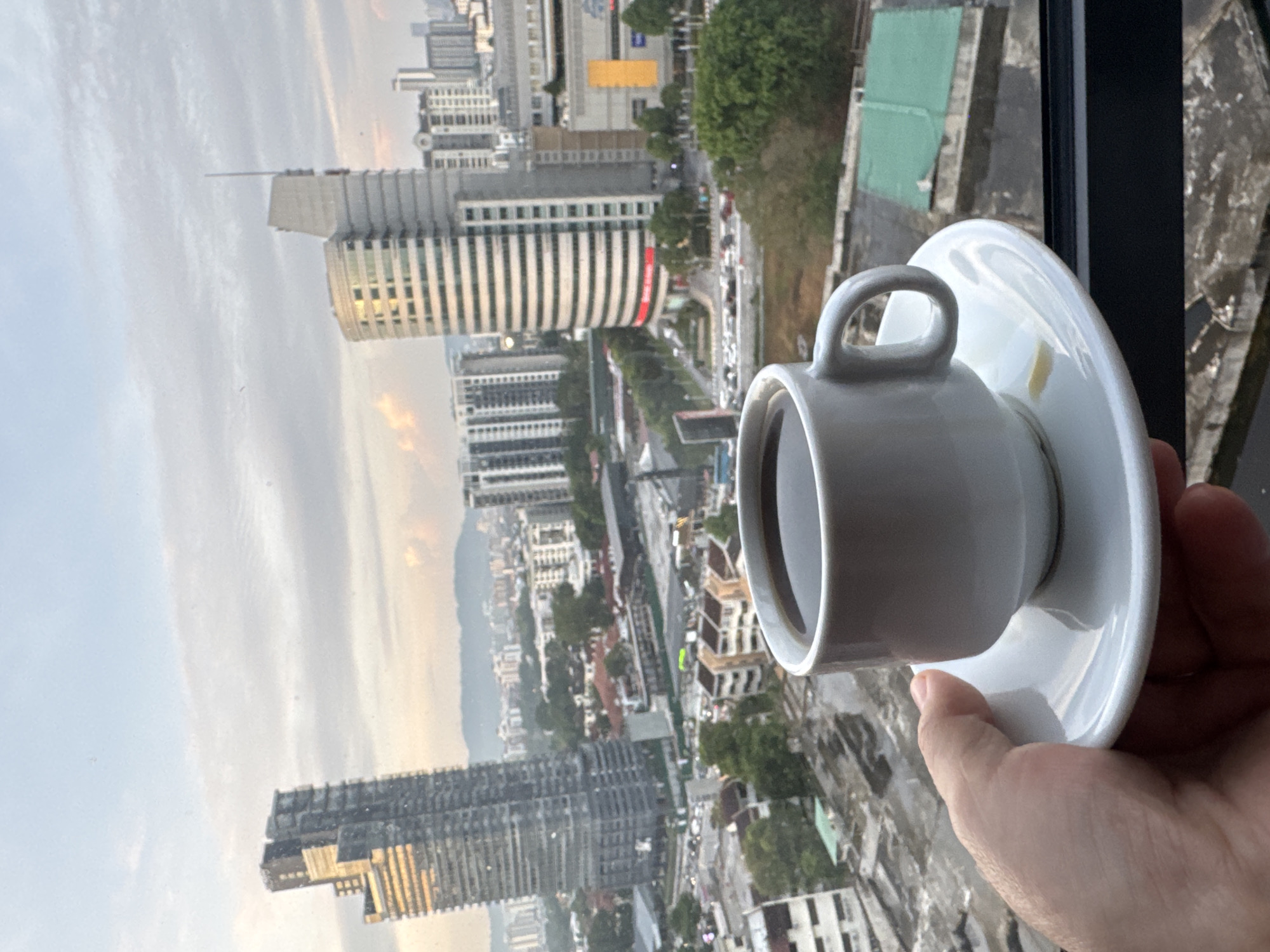 KL skyline at dusk, coffee in hand, city lights below
