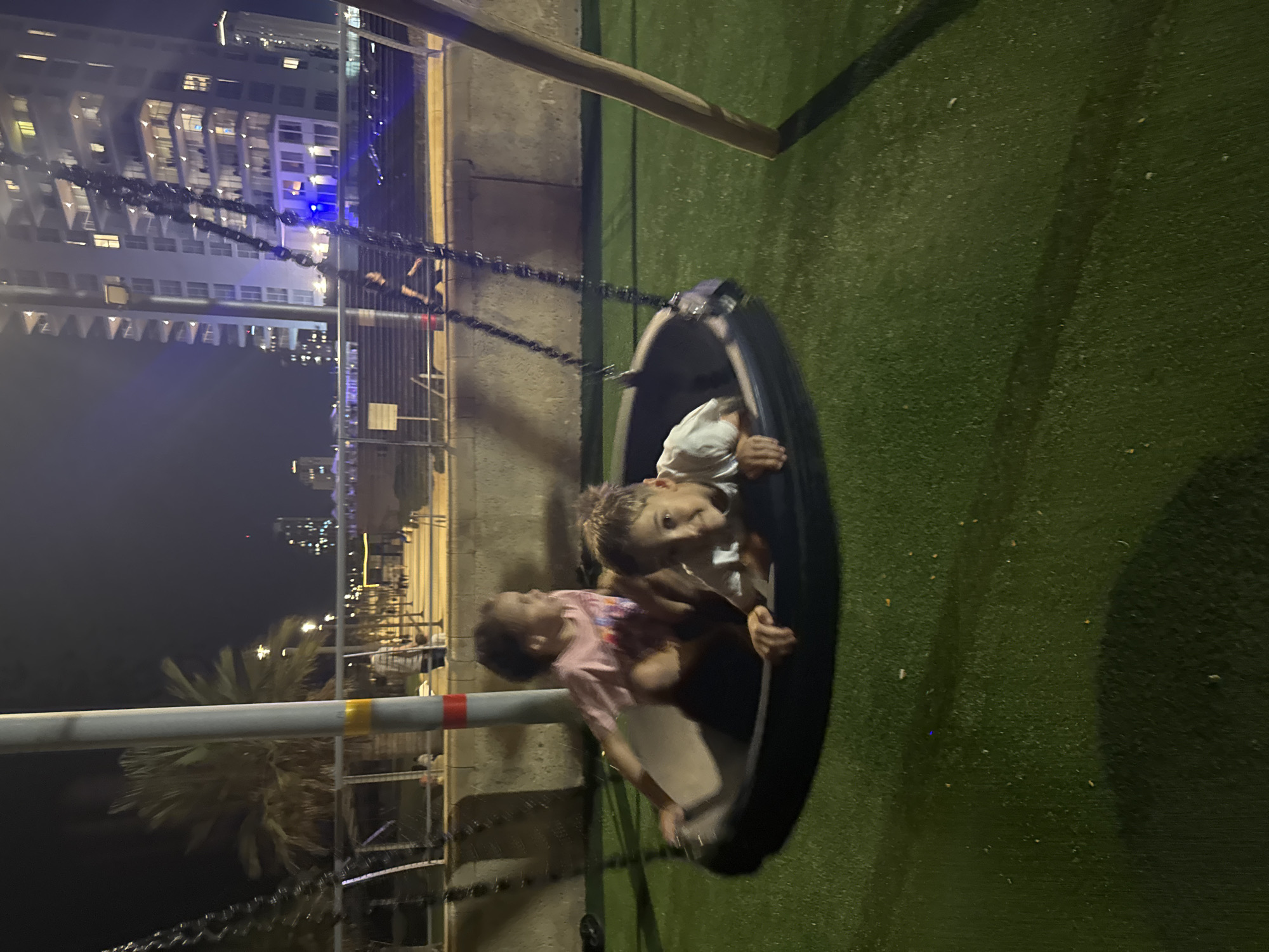 Kids on a tire swing, summer evening playground fun in Netanya