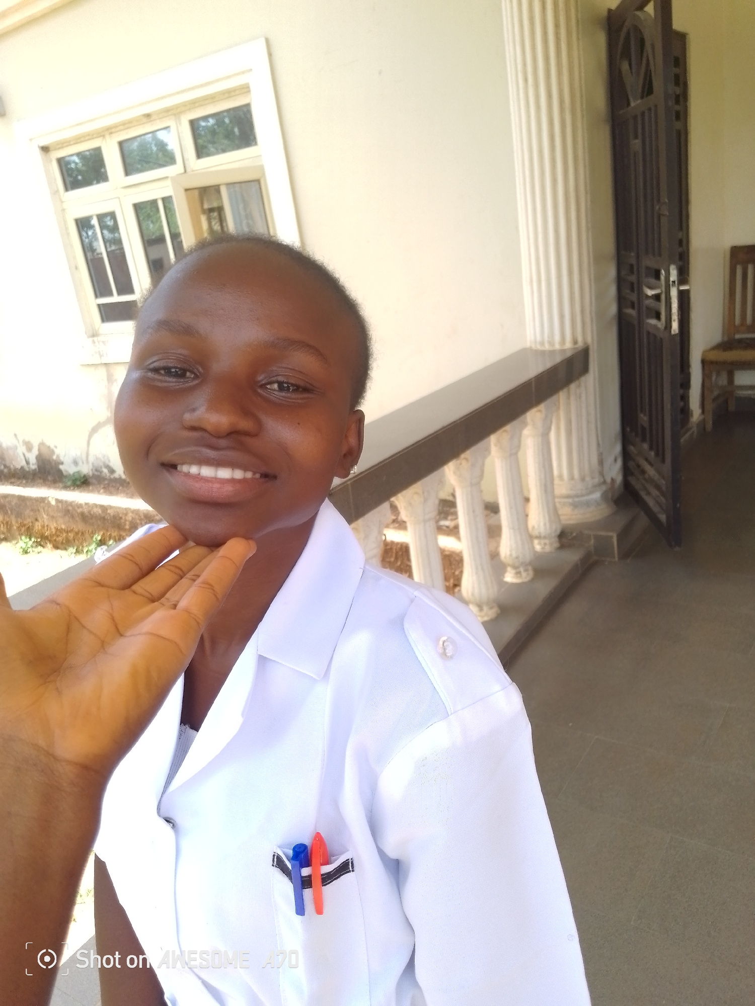 Healthcare worker photographed smiling outdoors in white uniform