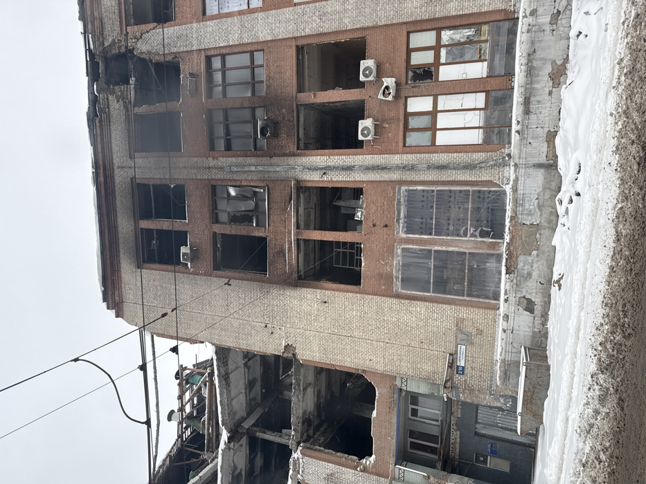 Woman in Toyota near damaged building during winter conditions