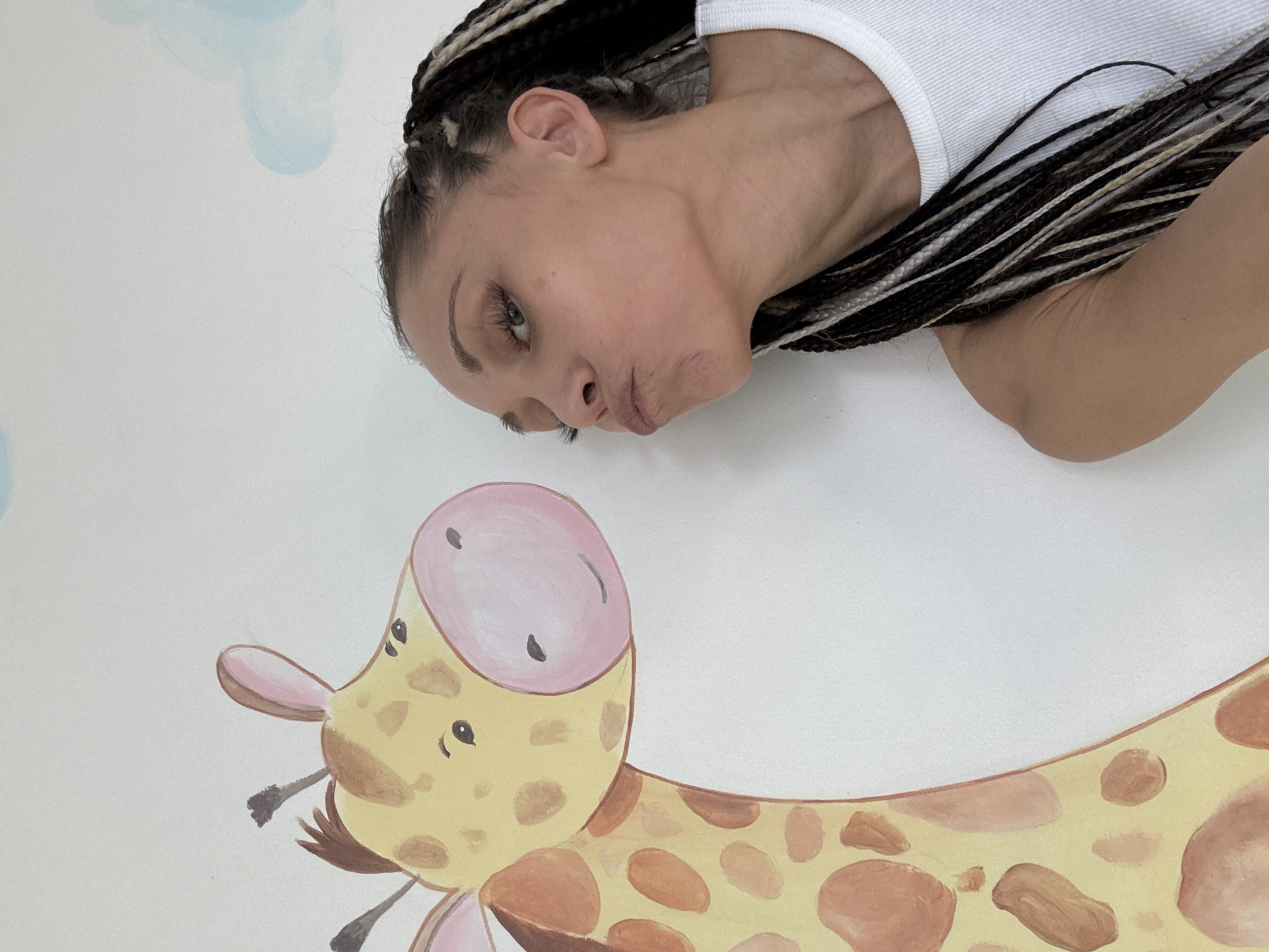 Woman and child play with water near giraffe mural