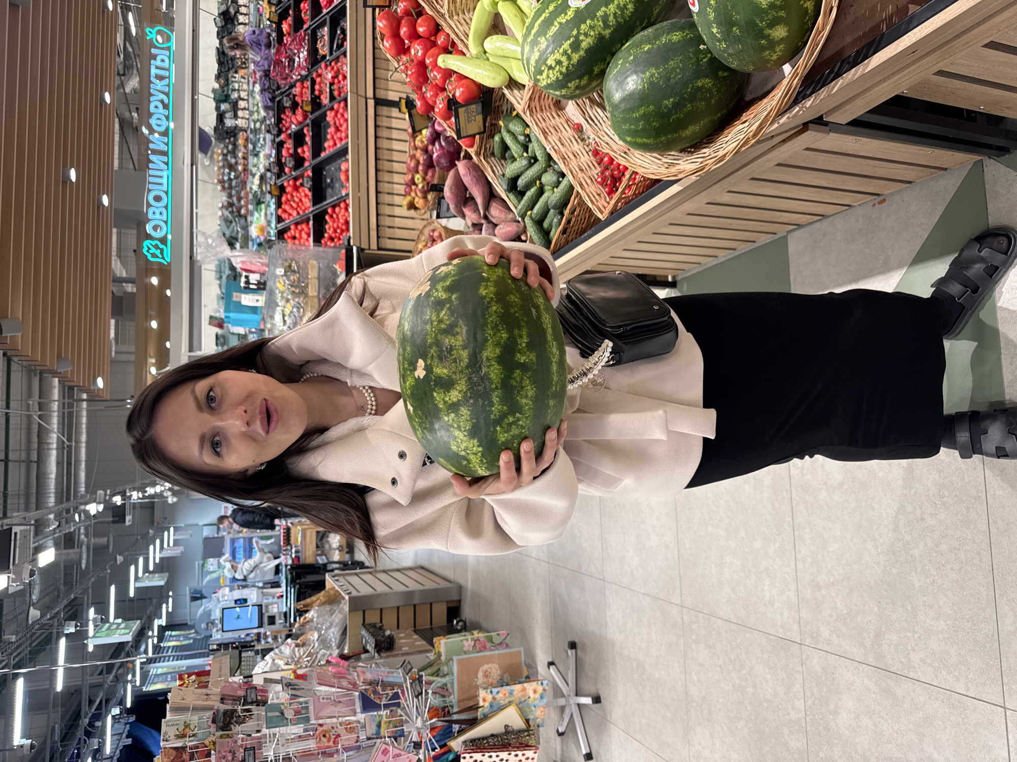 Woman shops for watermelon in grocery store produce section