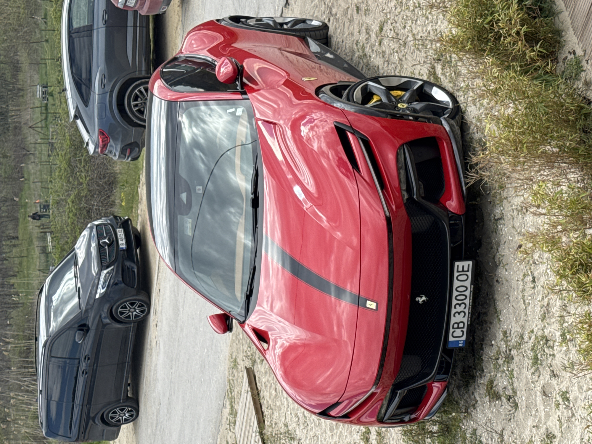 Red Ferrari parks alongside dirt path in Varna