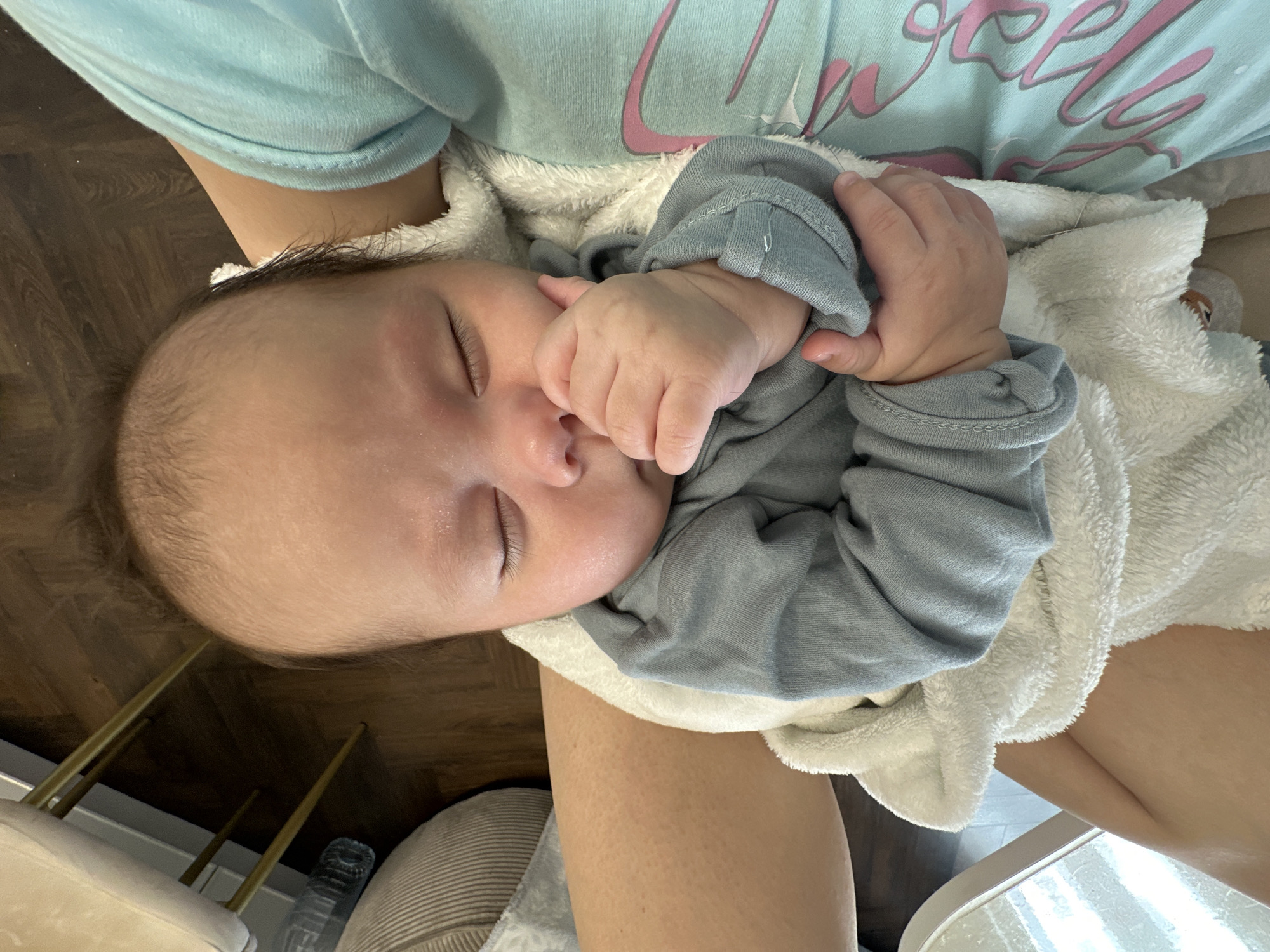 Infant sleeps peacefully in adult's arms during quiet afternoon moment