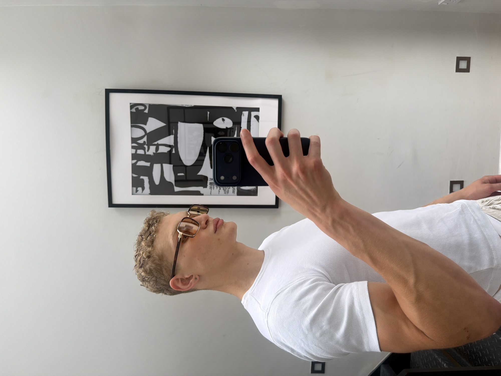 Mirror selfie in a minimal white room, London