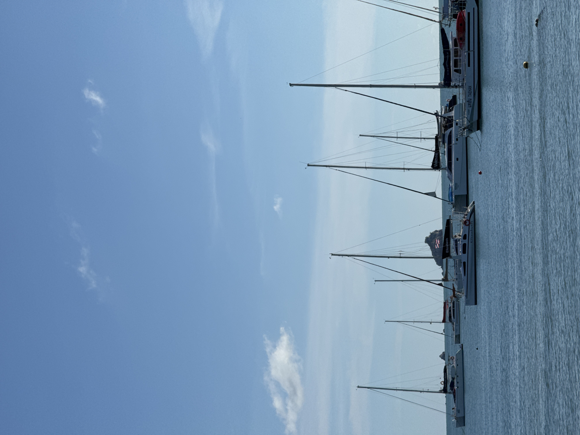 Lazy beach morning with sailboats, lounge chairs, and calm water