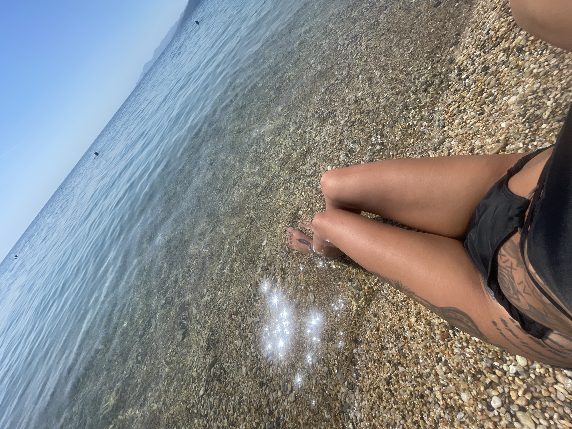 Tattooed beachgoer enjoys morning at Nea Vrasna coastal resort