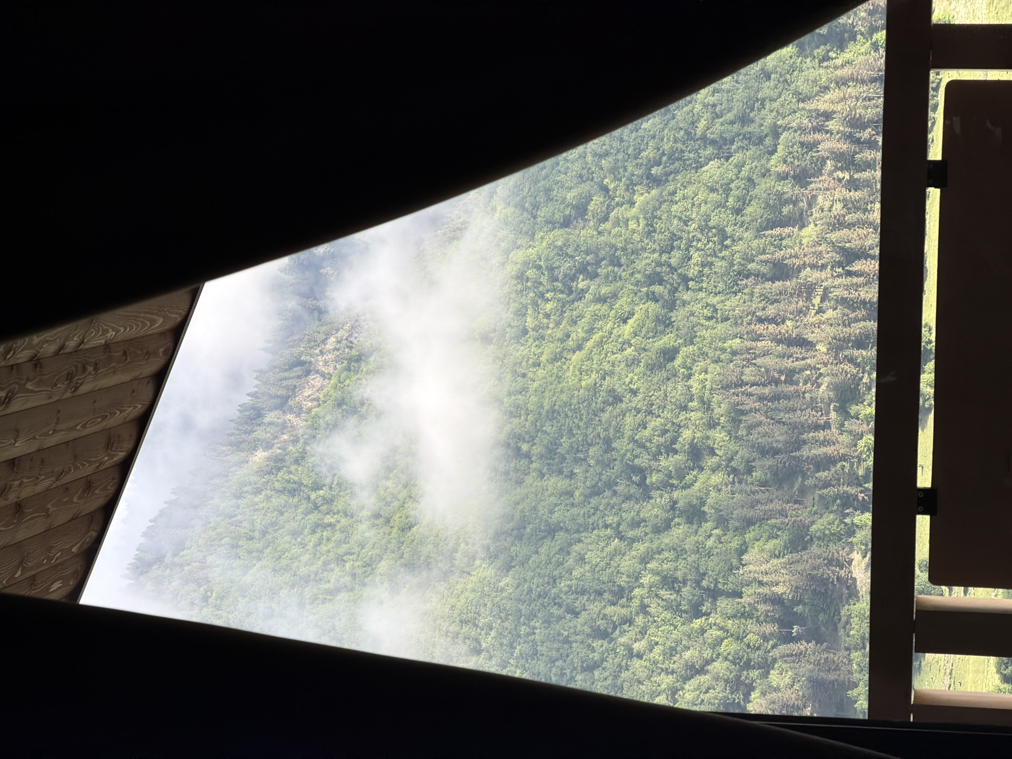 Foggy forested mountainside seen through a window in Mestia