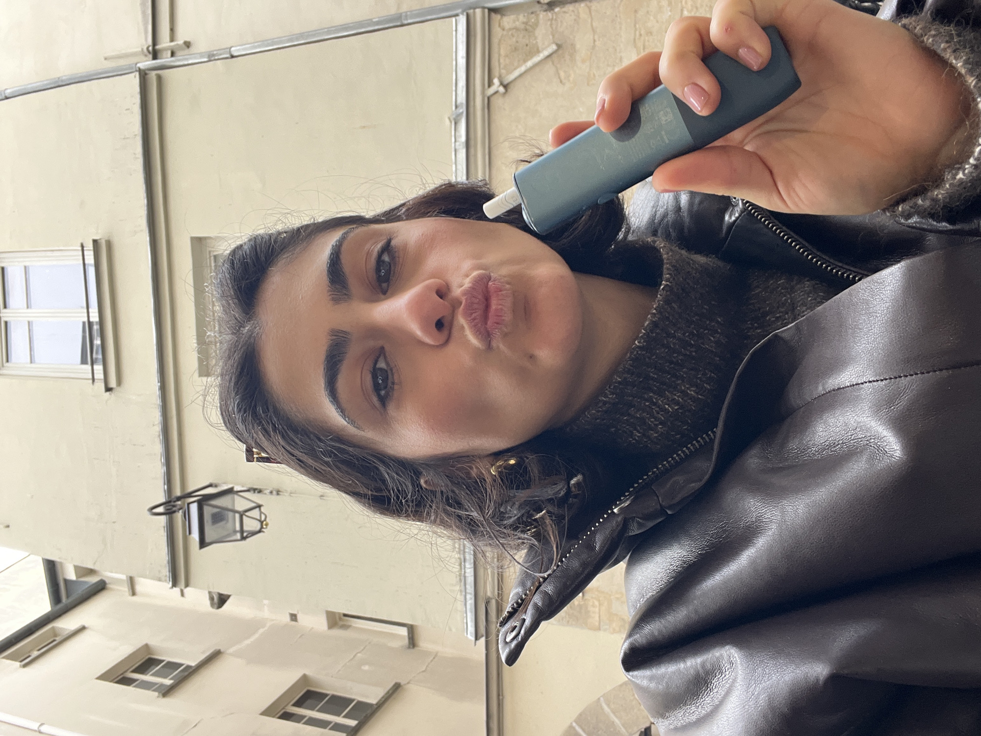 Woman takes selfies in Parisian courtyard near Le Temple