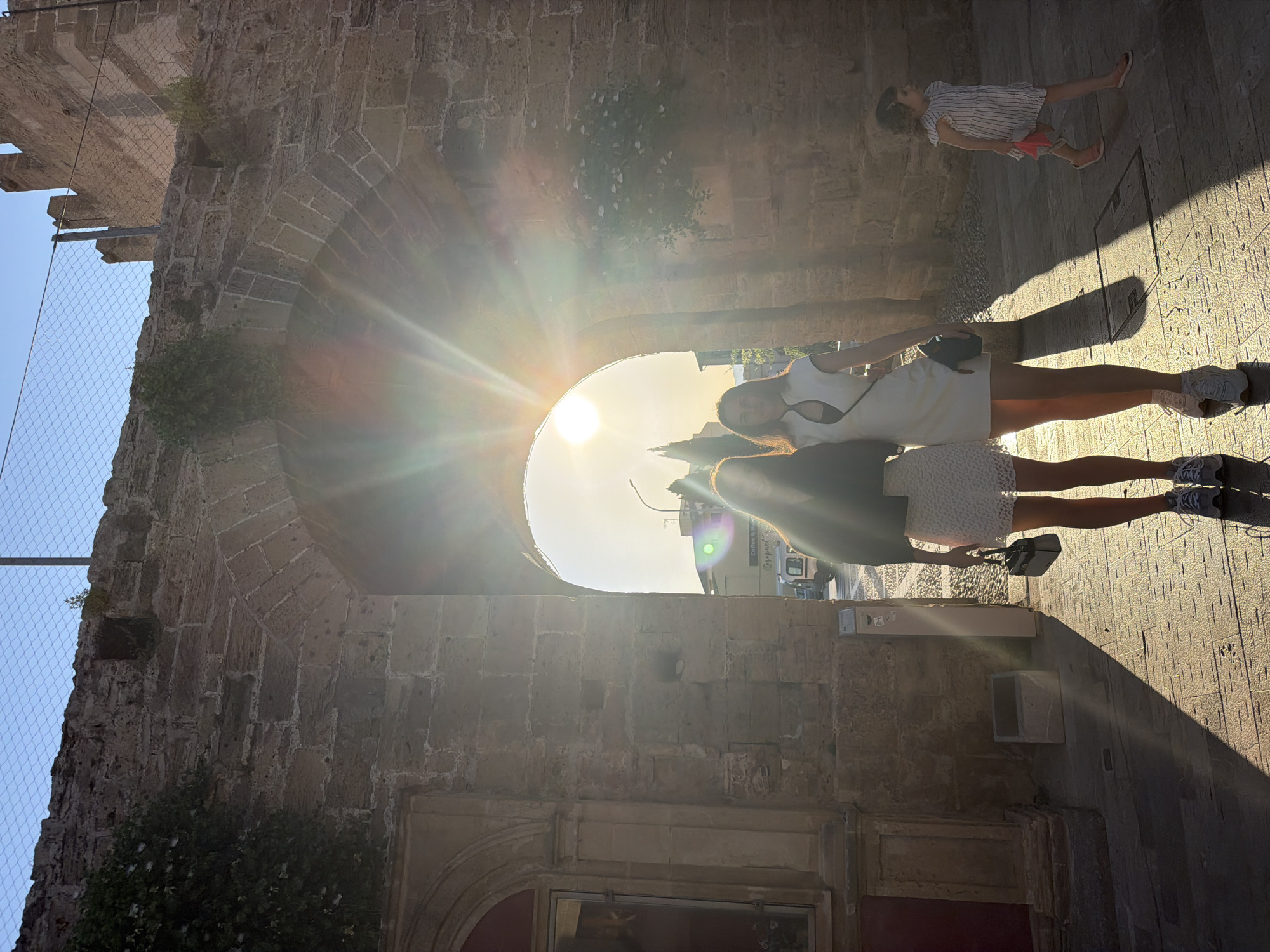 Women photographed walking near medieval walls in Alcúdia, Spain