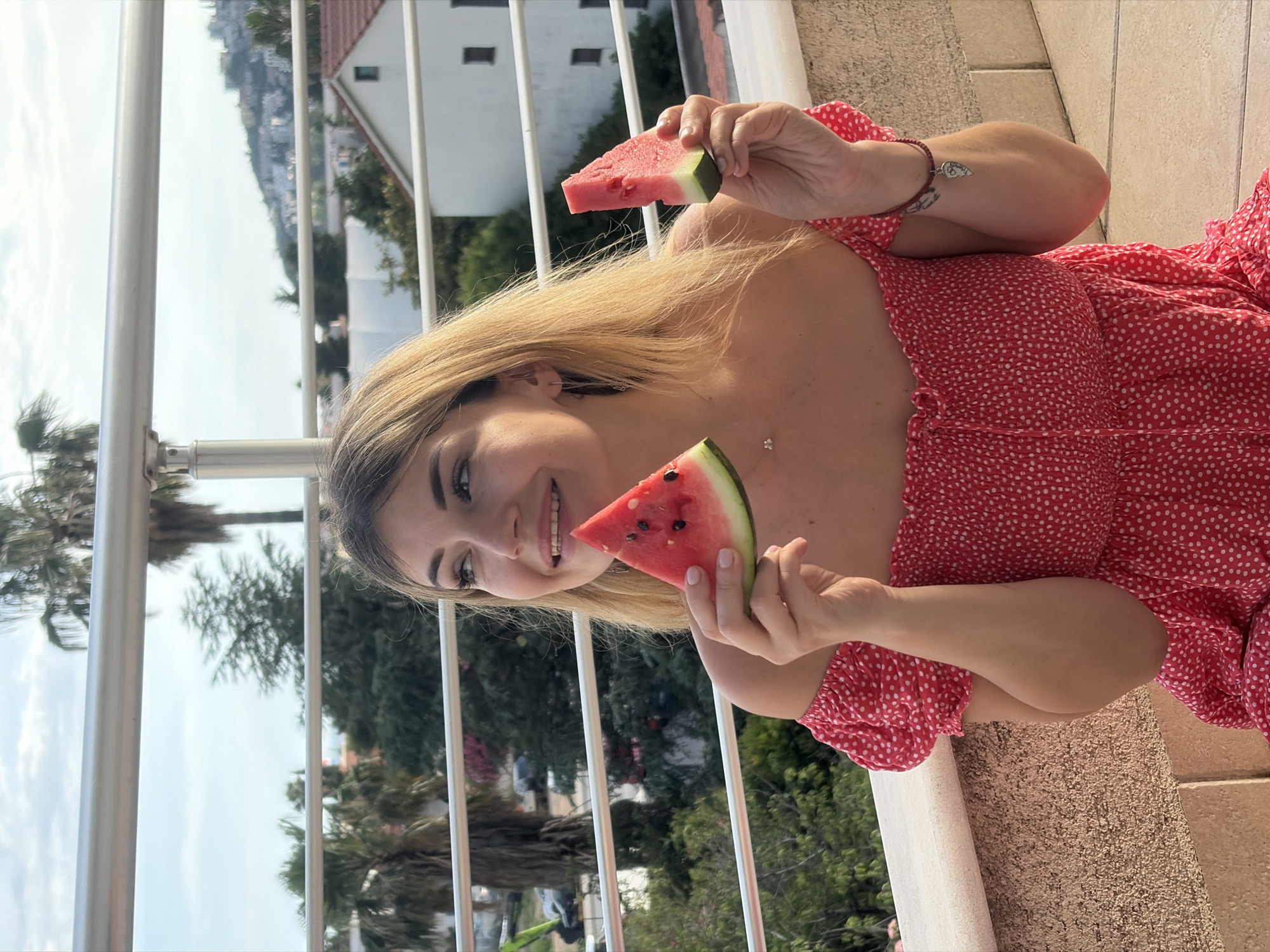 Woman enjoys watermelon snack on Budva balcony with companions