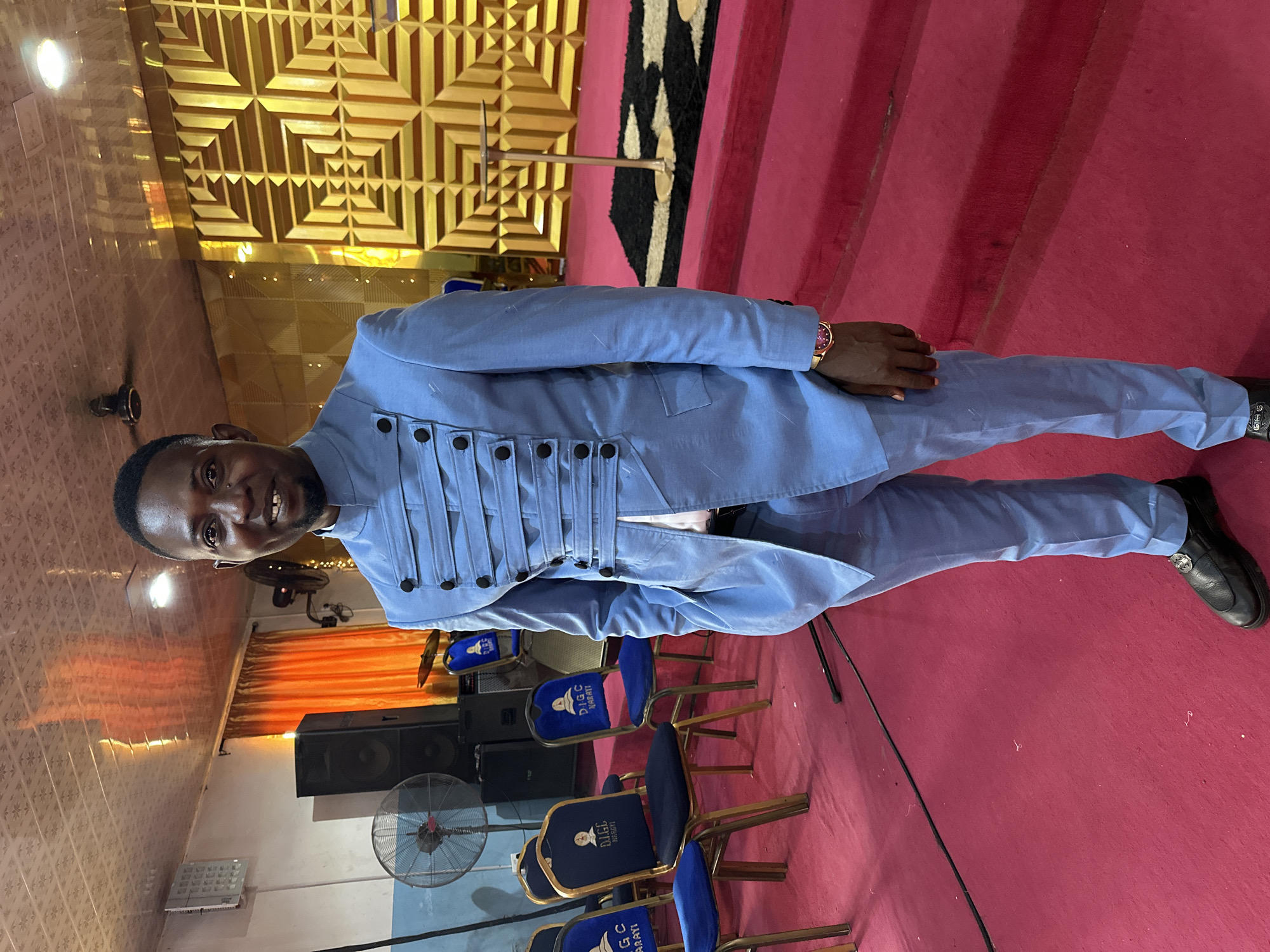 Light blue suit on a red-carpeted stage in Narayi, Nigeria