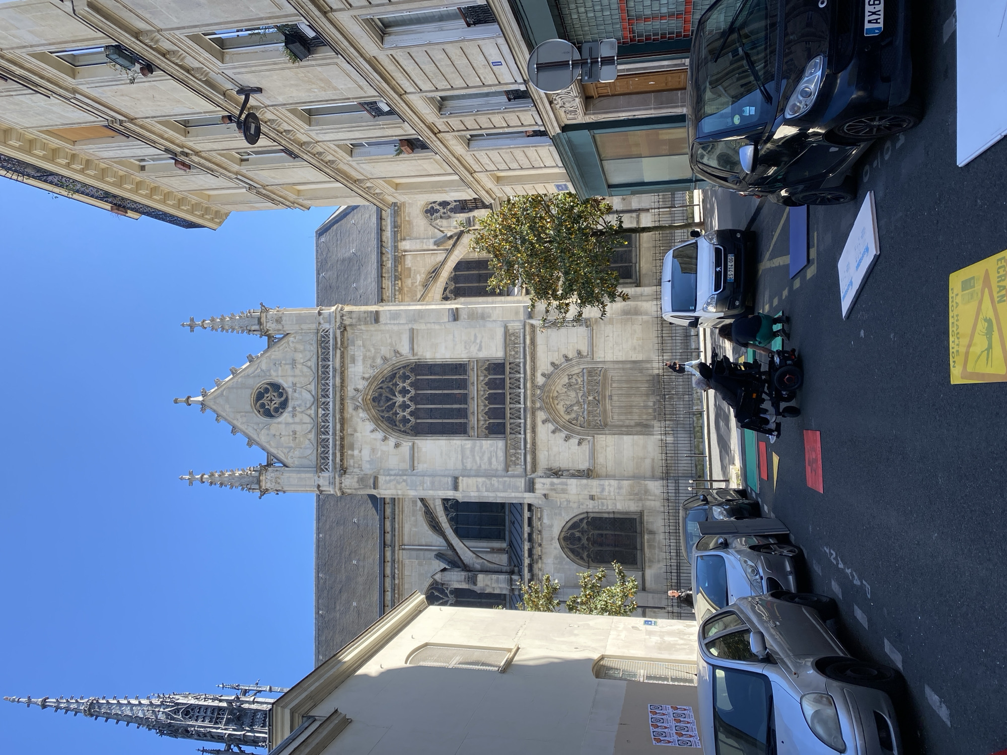 Sunny Paris street scene features prominent Gothic church