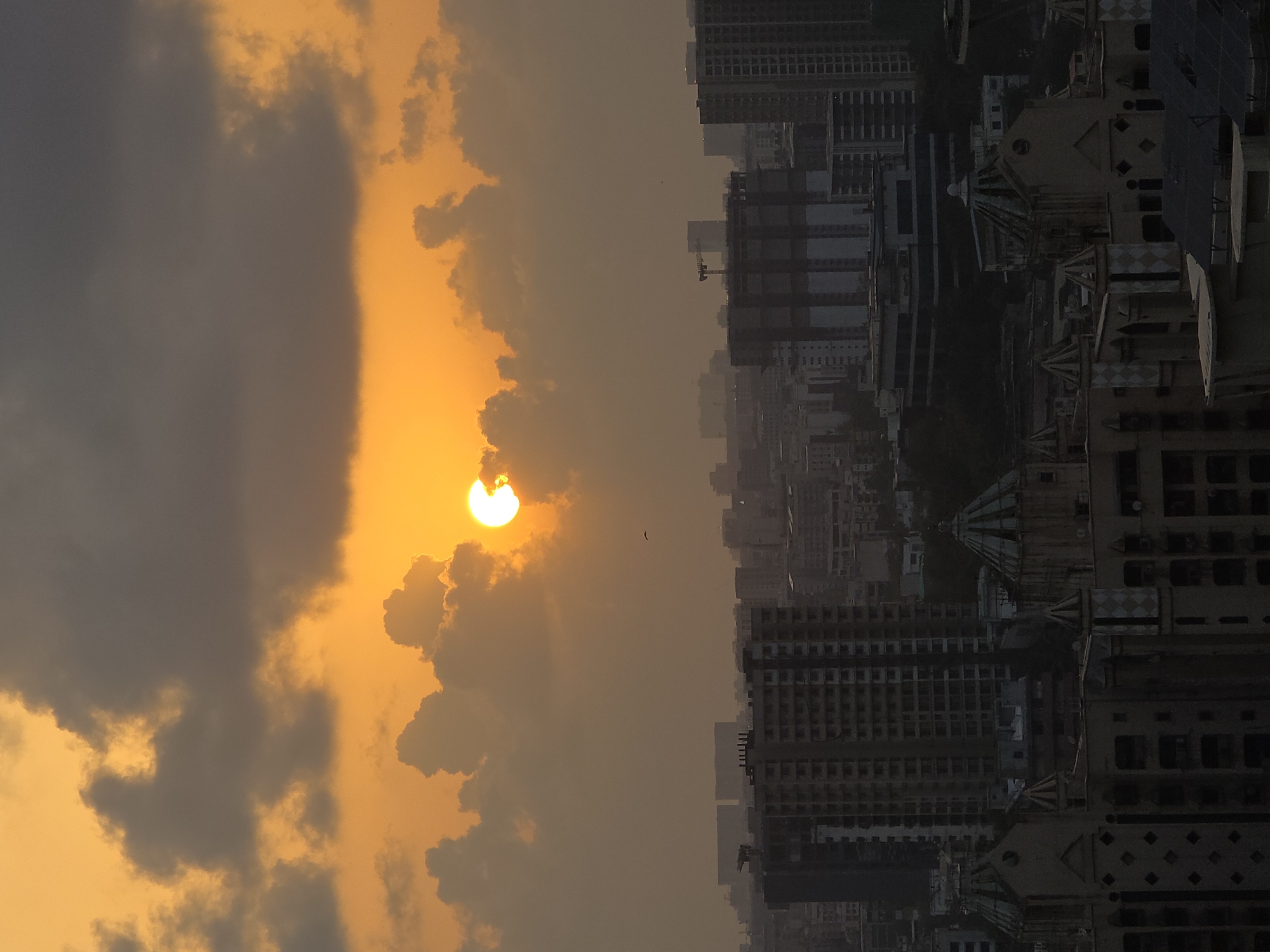 Sunset observed over Mumbai cityscape amid cloudy skies