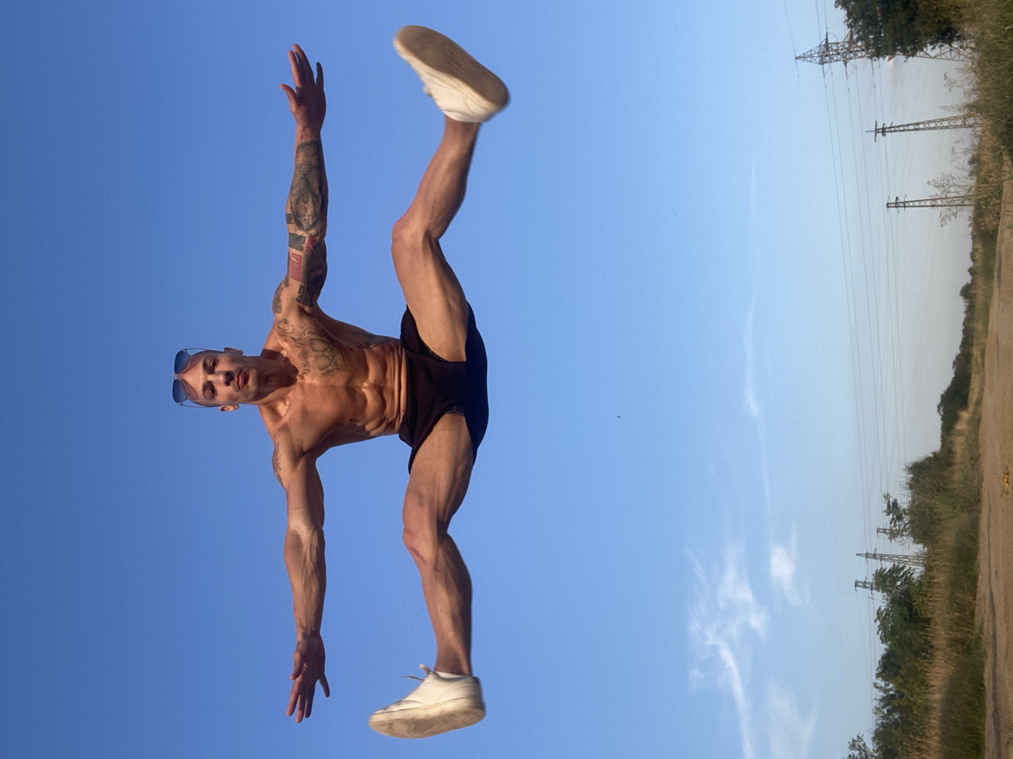 Tattooed jumper splits mid-air against a blue sky in Pleven