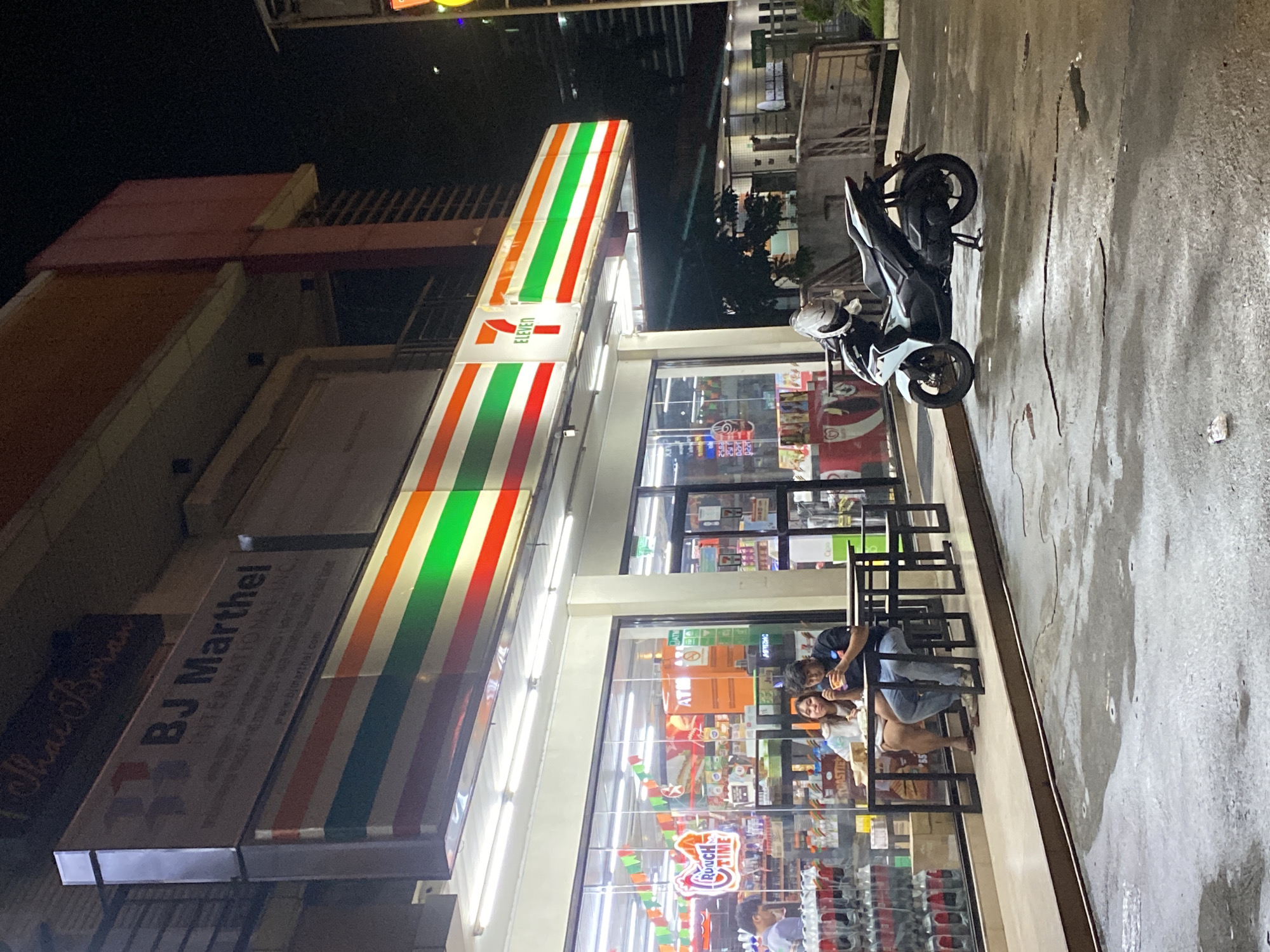 Wet Davao City streets at night, commercial strip in motion