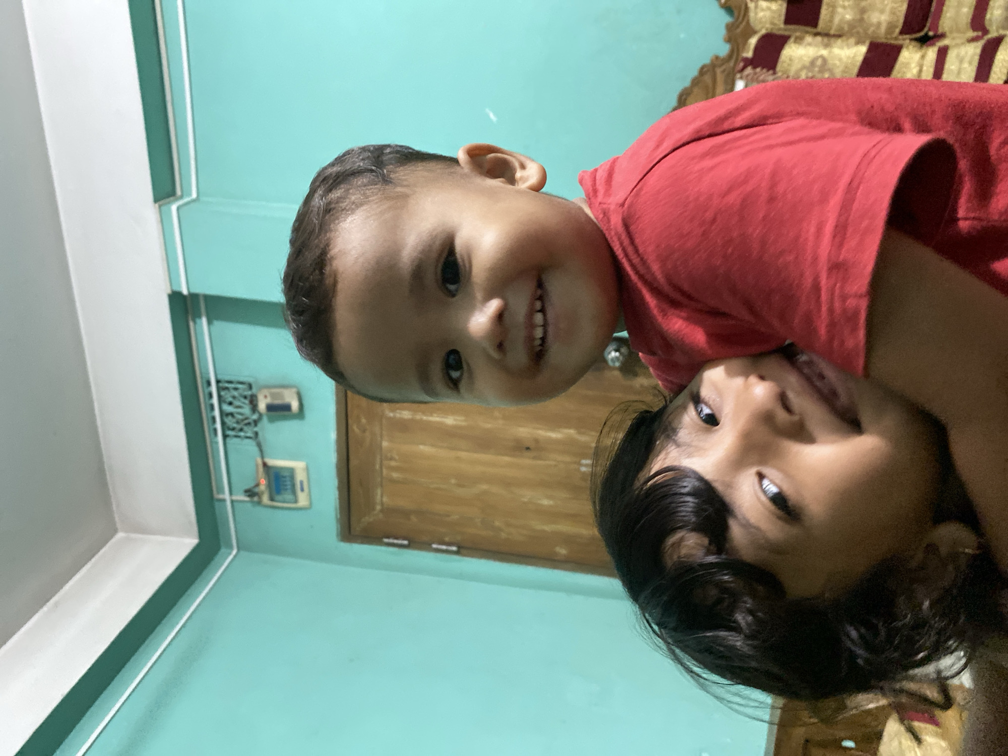 Children share tender moment indoors in Dhaka