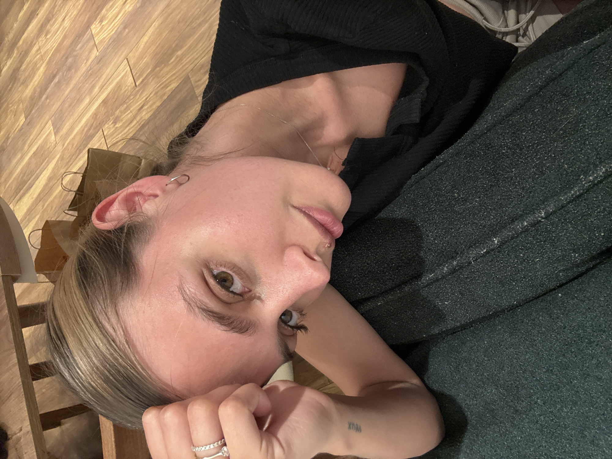 Person rests on wooden floor with shopping bag nearby