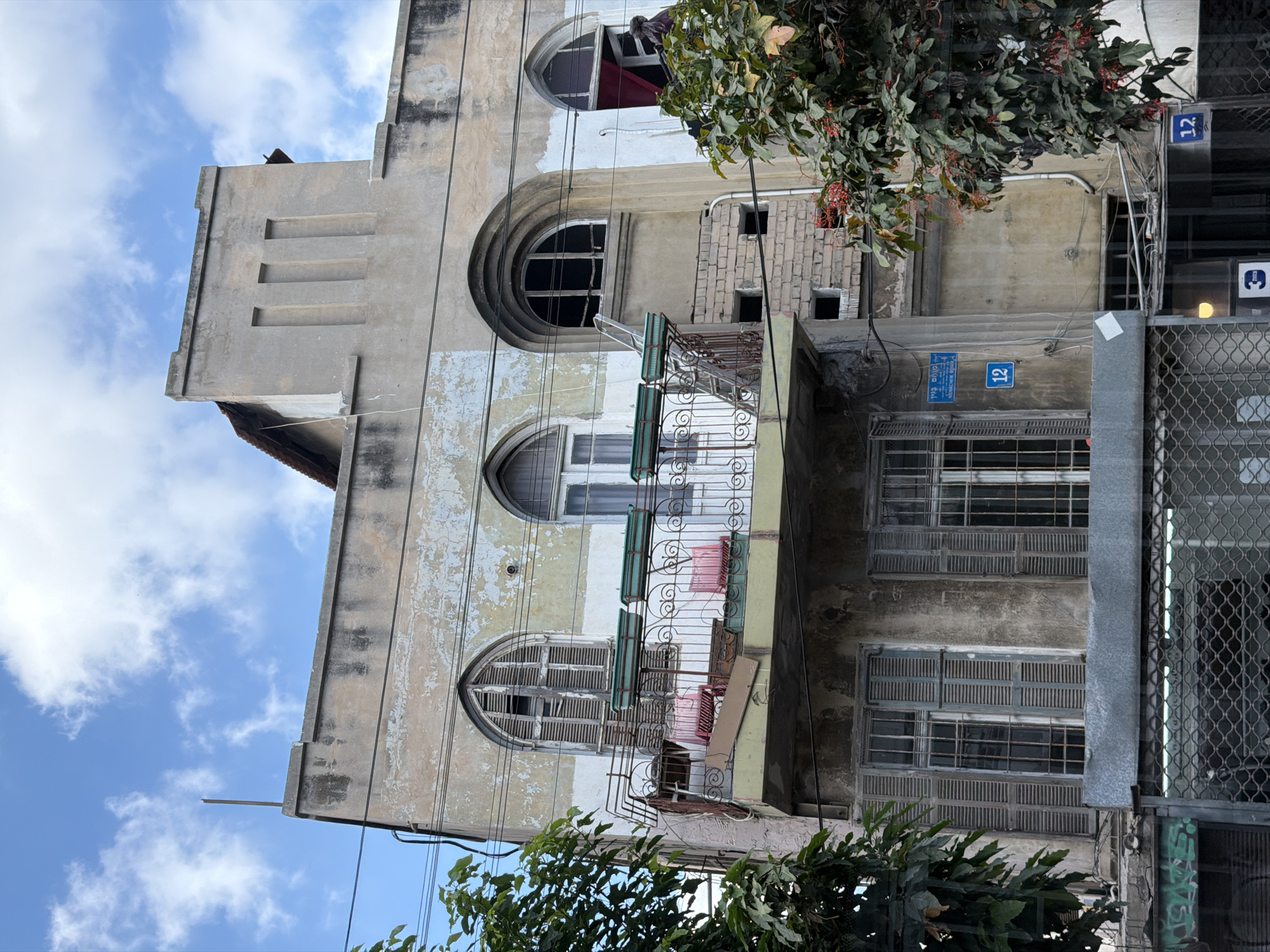 A Tel Aviv block: weathered buildings, parked cars, morning cyclist