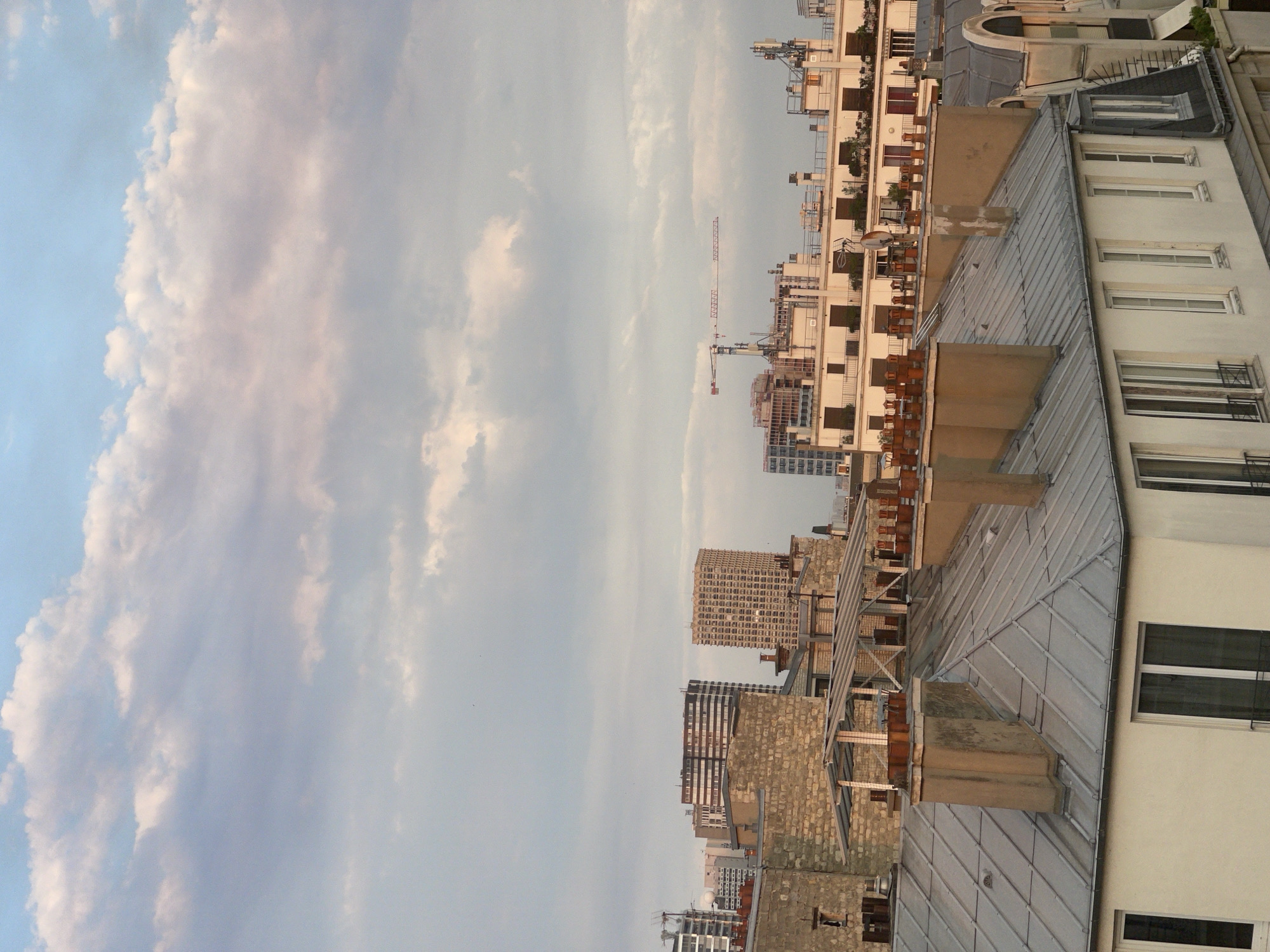 Paris rooftops glow under a July evening sky