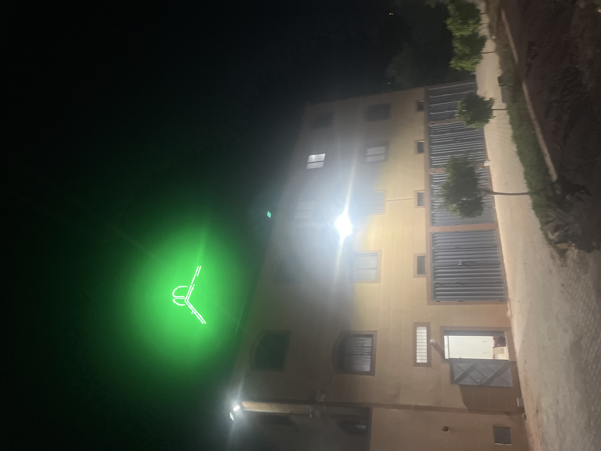 Spotlit building with green neon sign observed in Ouaouizert