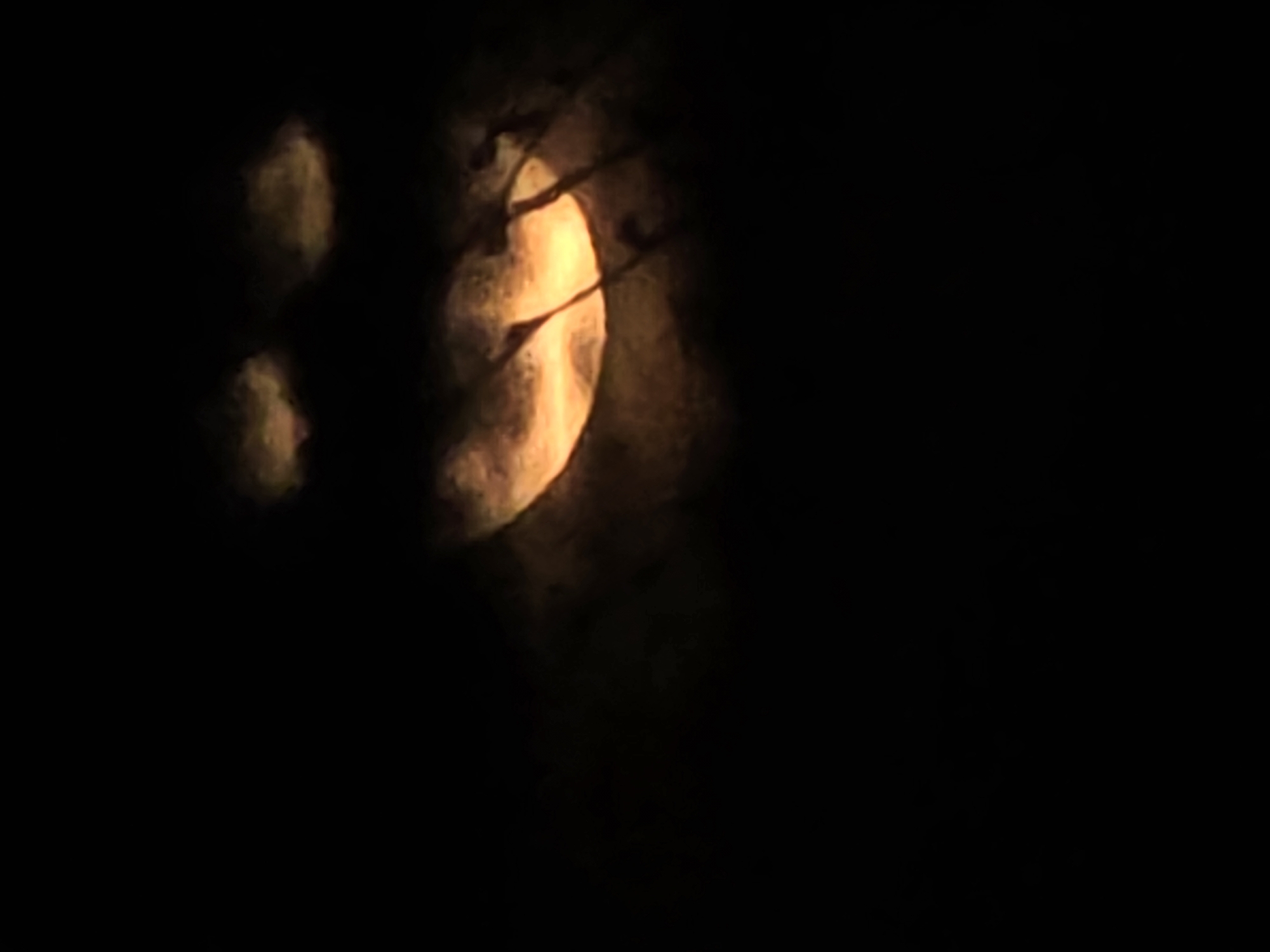 Orange moon observed through clouds over urban area