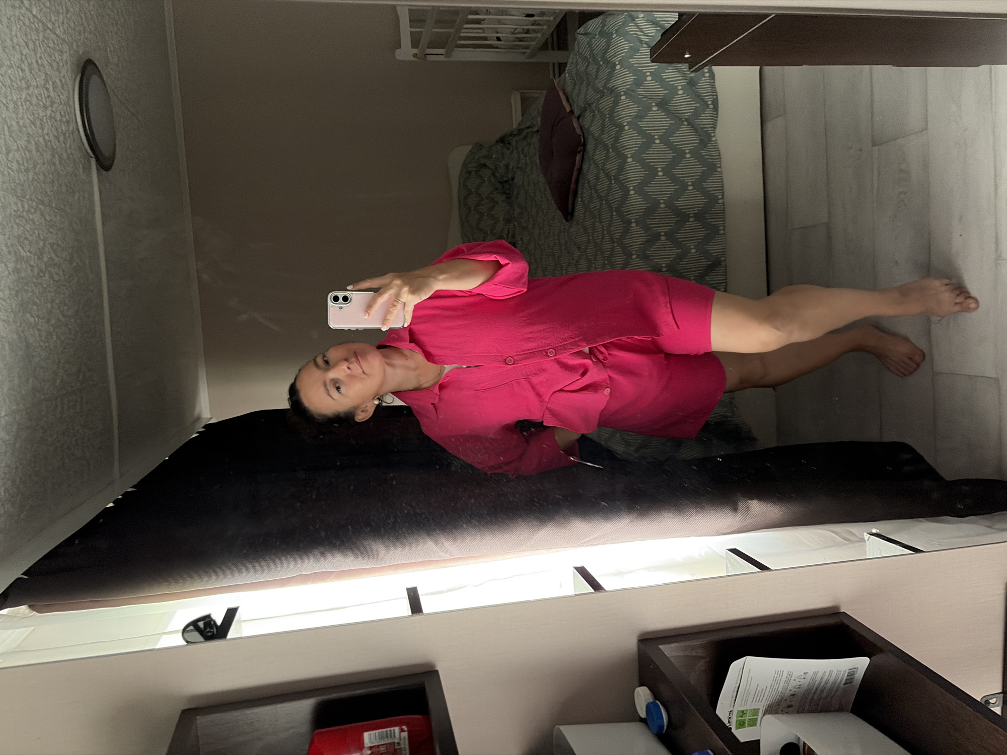 Mirror selfie in a pink outfit, bedroom with crib in background