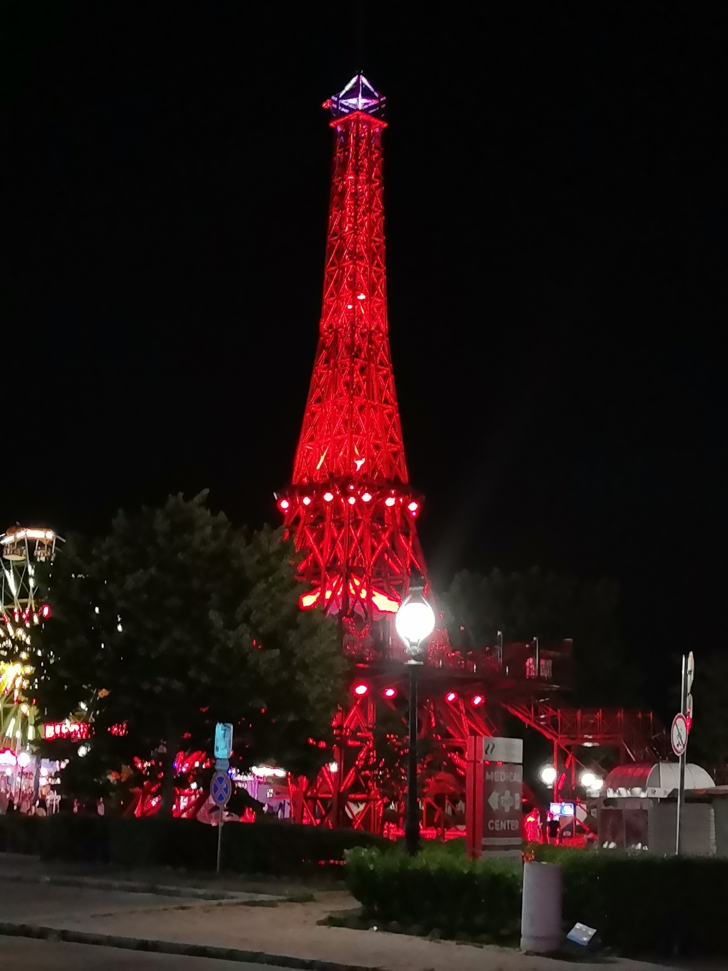 Red-lit tower and beachside nightlife on a summer evening