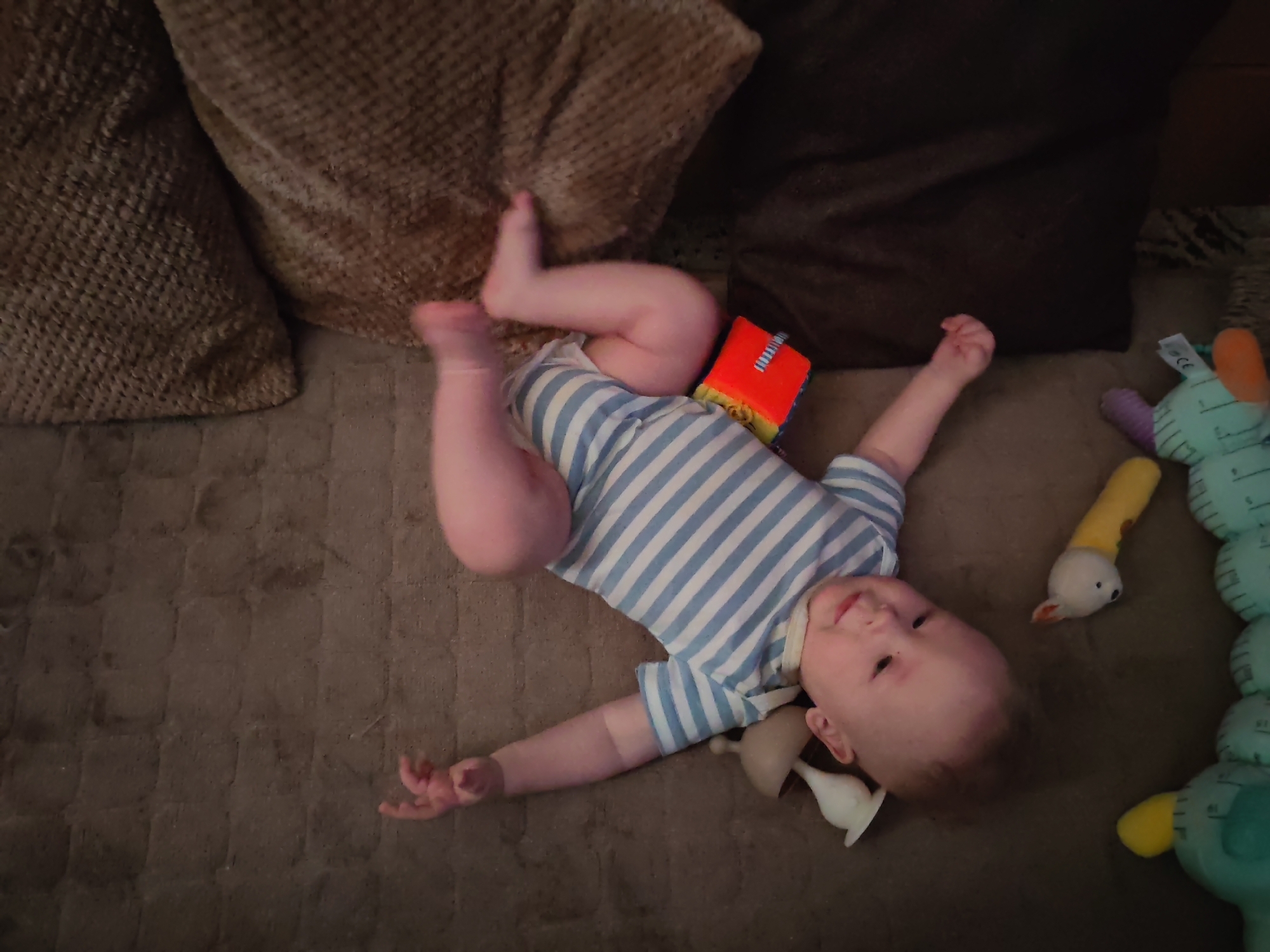 Baby on carpeted floor surrounded by toys, Mezhdurechensk
