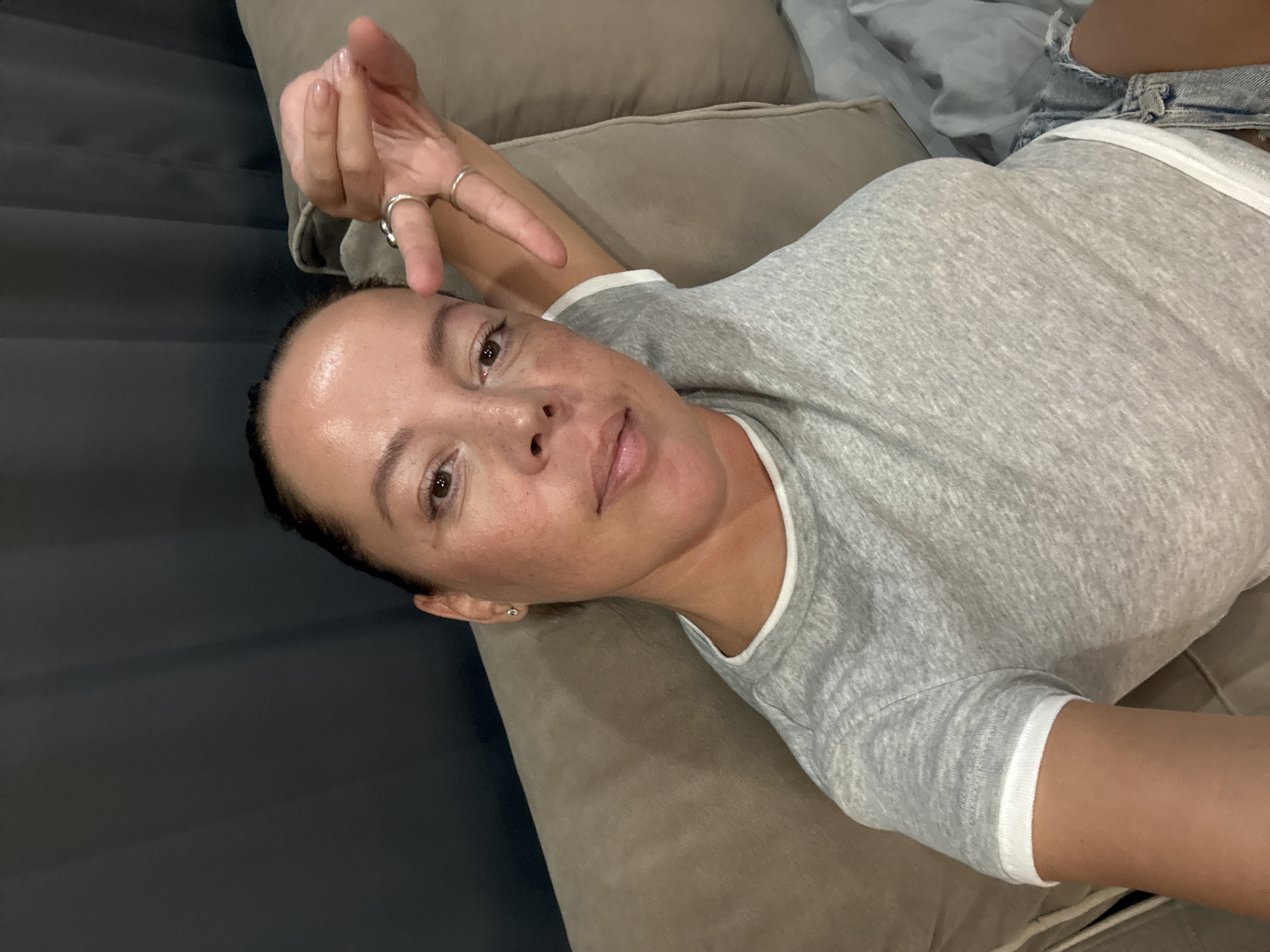 Couch hang, peace sign, casual indoor vibe.