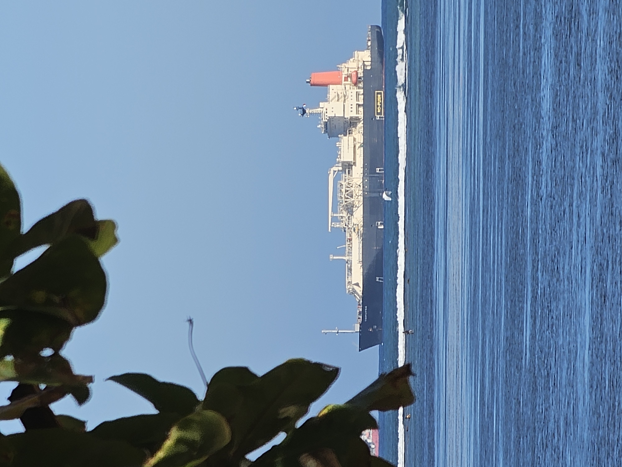 Jukung boats and cargo ships along a Bali morning shoreline