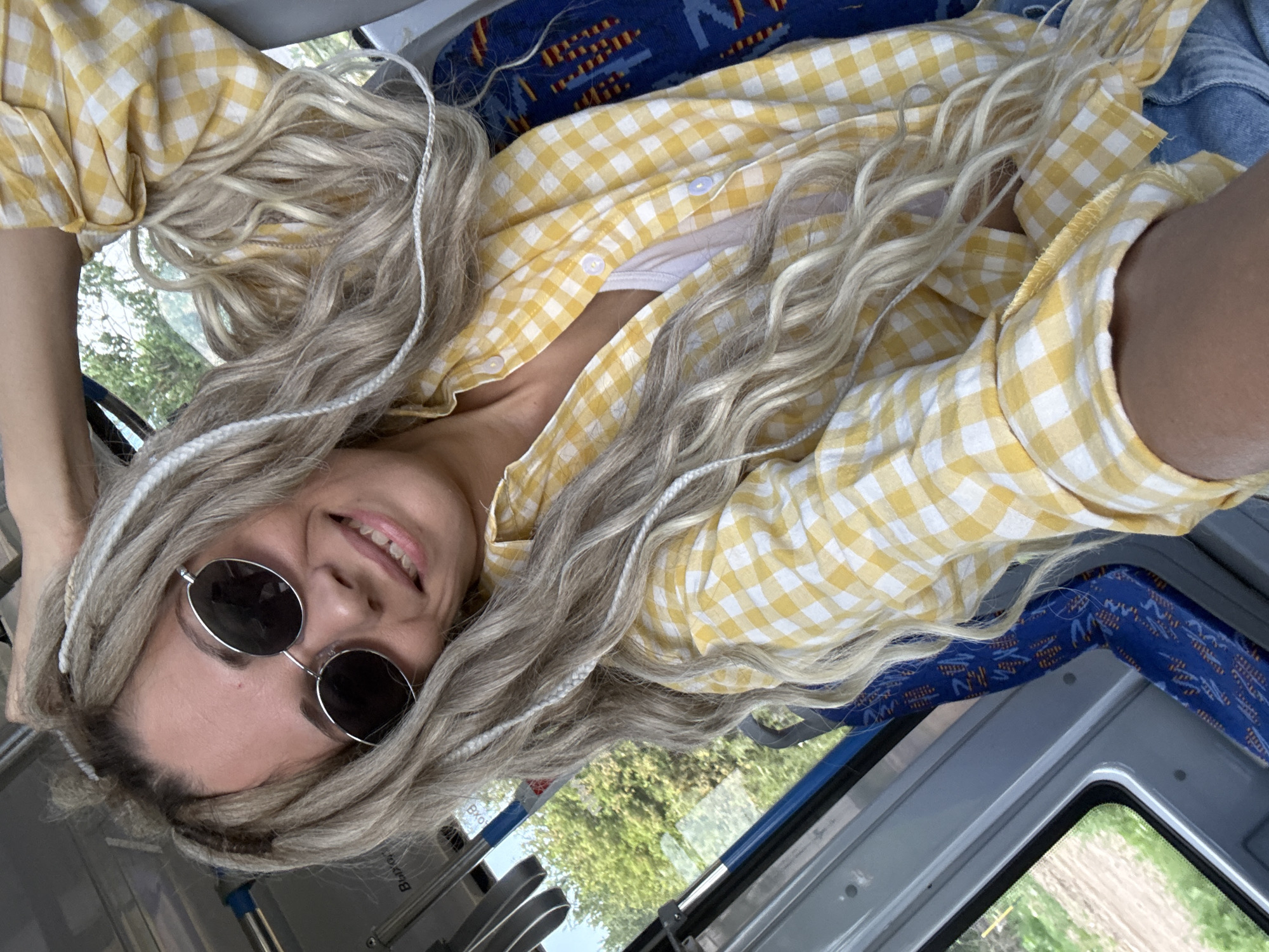 Woman with dreadlocks smiles on bus in Rusanovo