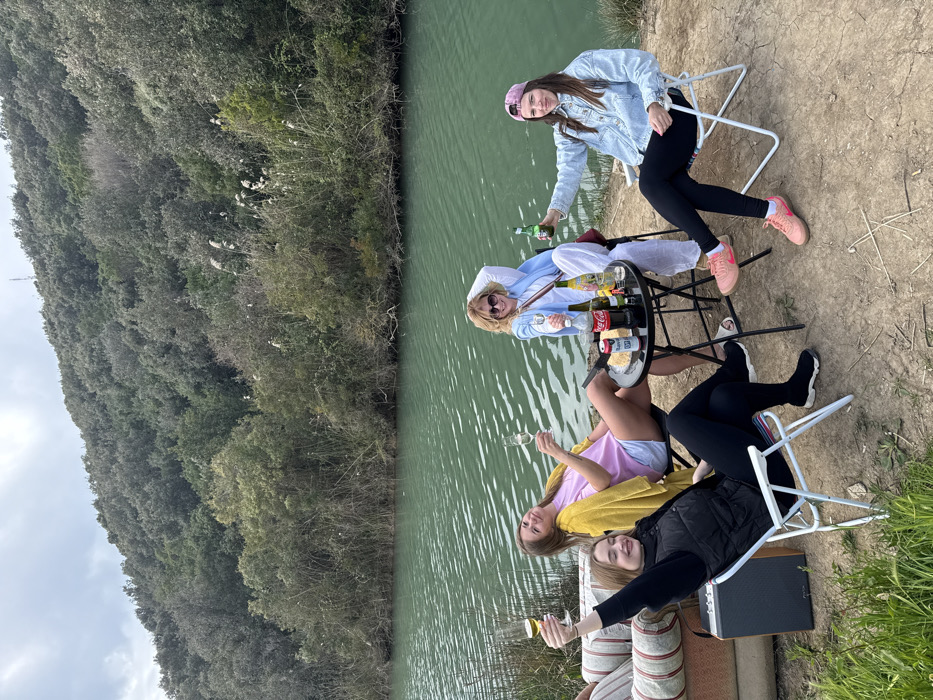 Four women gather by green waters in Prijevor, Montenegro