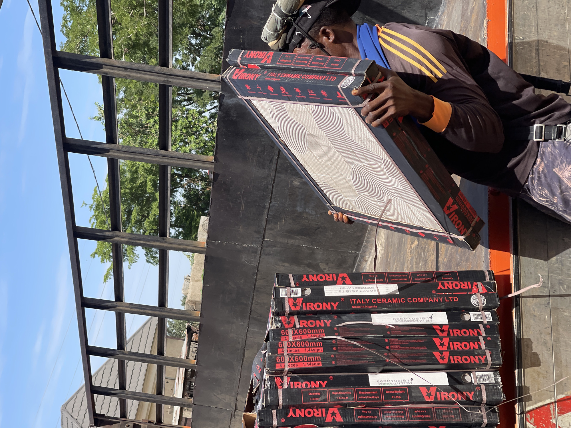 Workers unload ceramic tiles from container in Abuja showroom