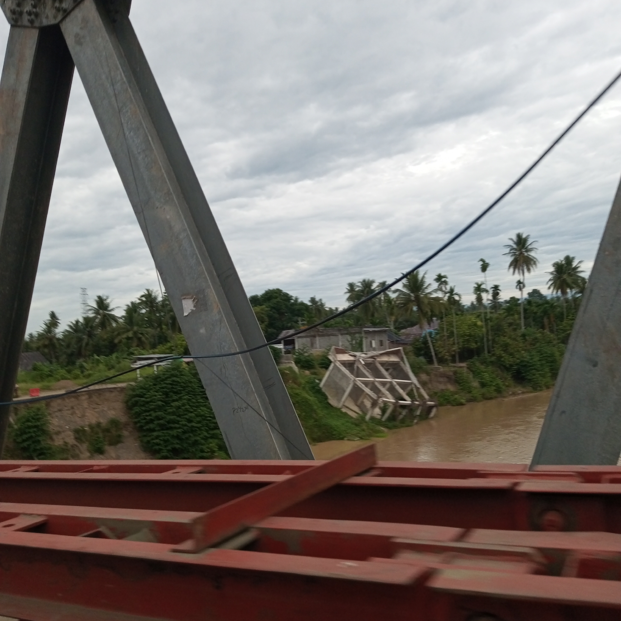 Overloaded truck and collapsed bridge structure along Aceh river corridor
