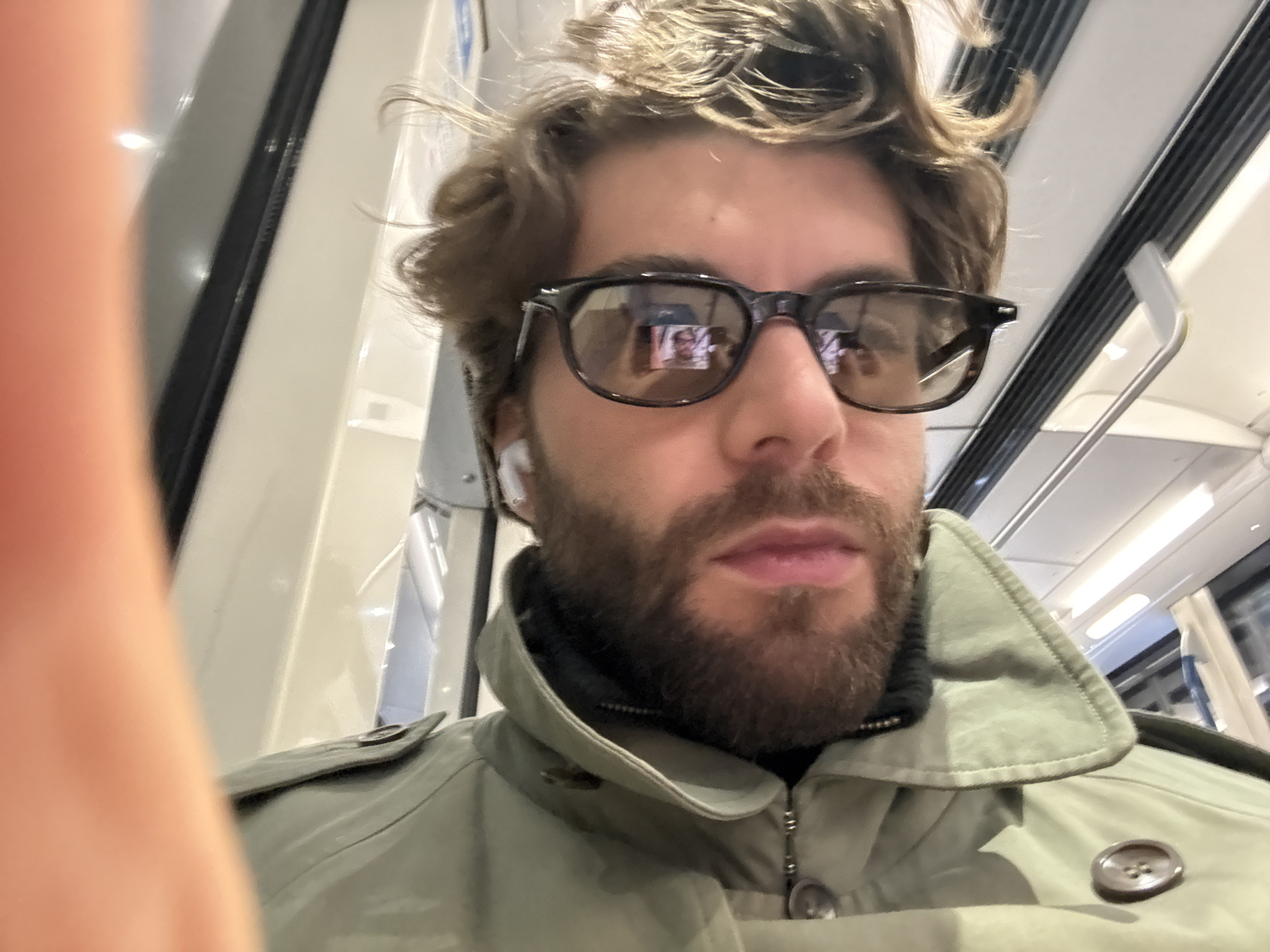 Evening commuter rides Montreal Metro in olive trench coat