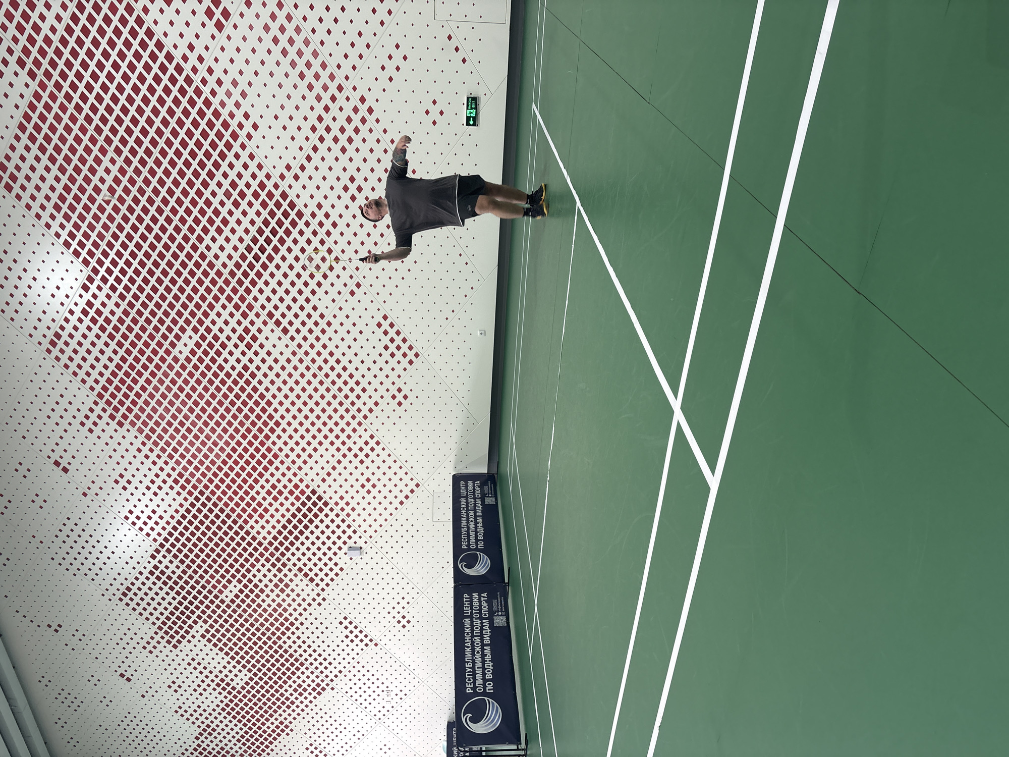 Badminton player mid-swing on an indoor court in Minsk