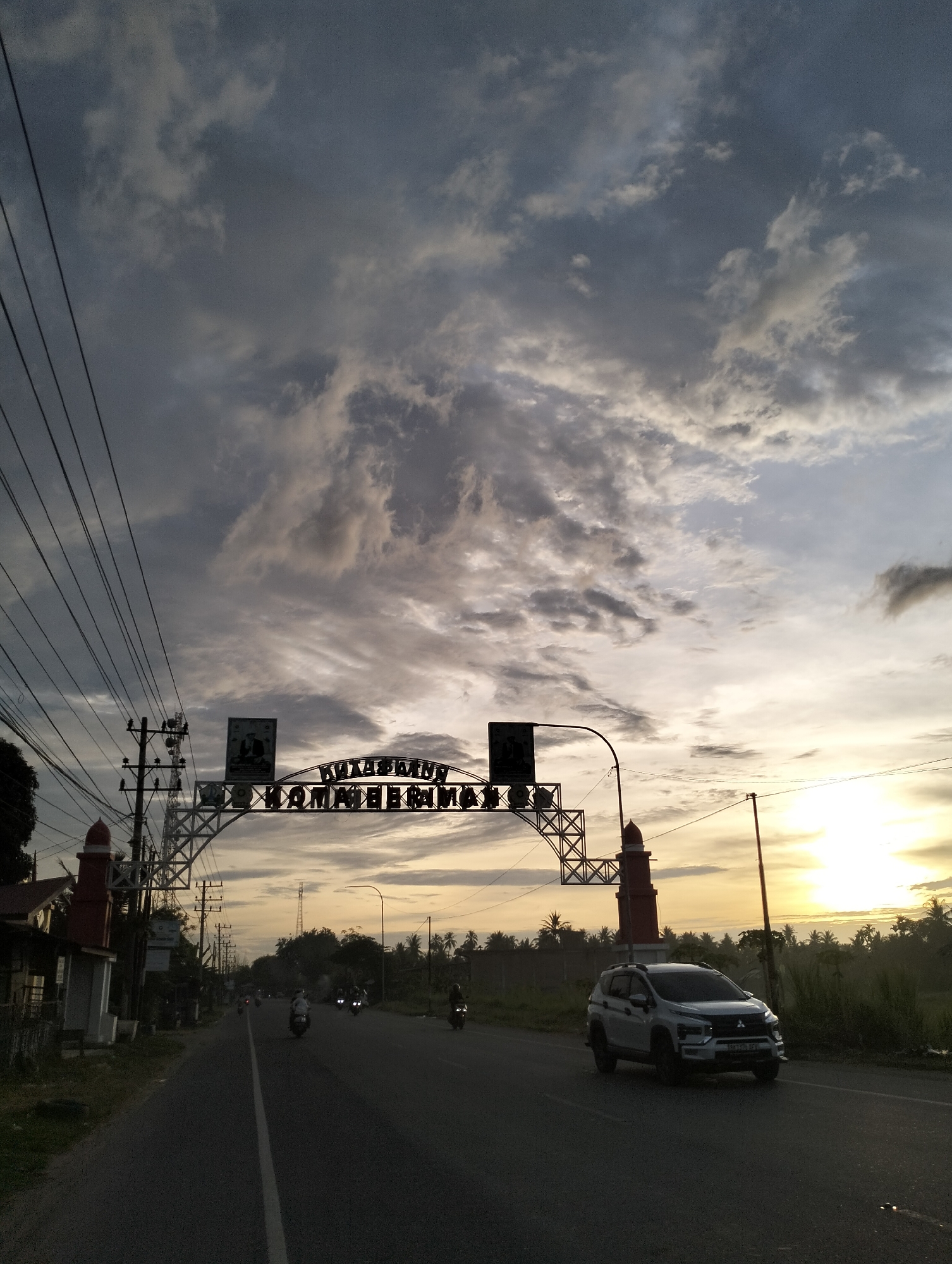 White car travels road under cloudy skies in Tingkeummanyang