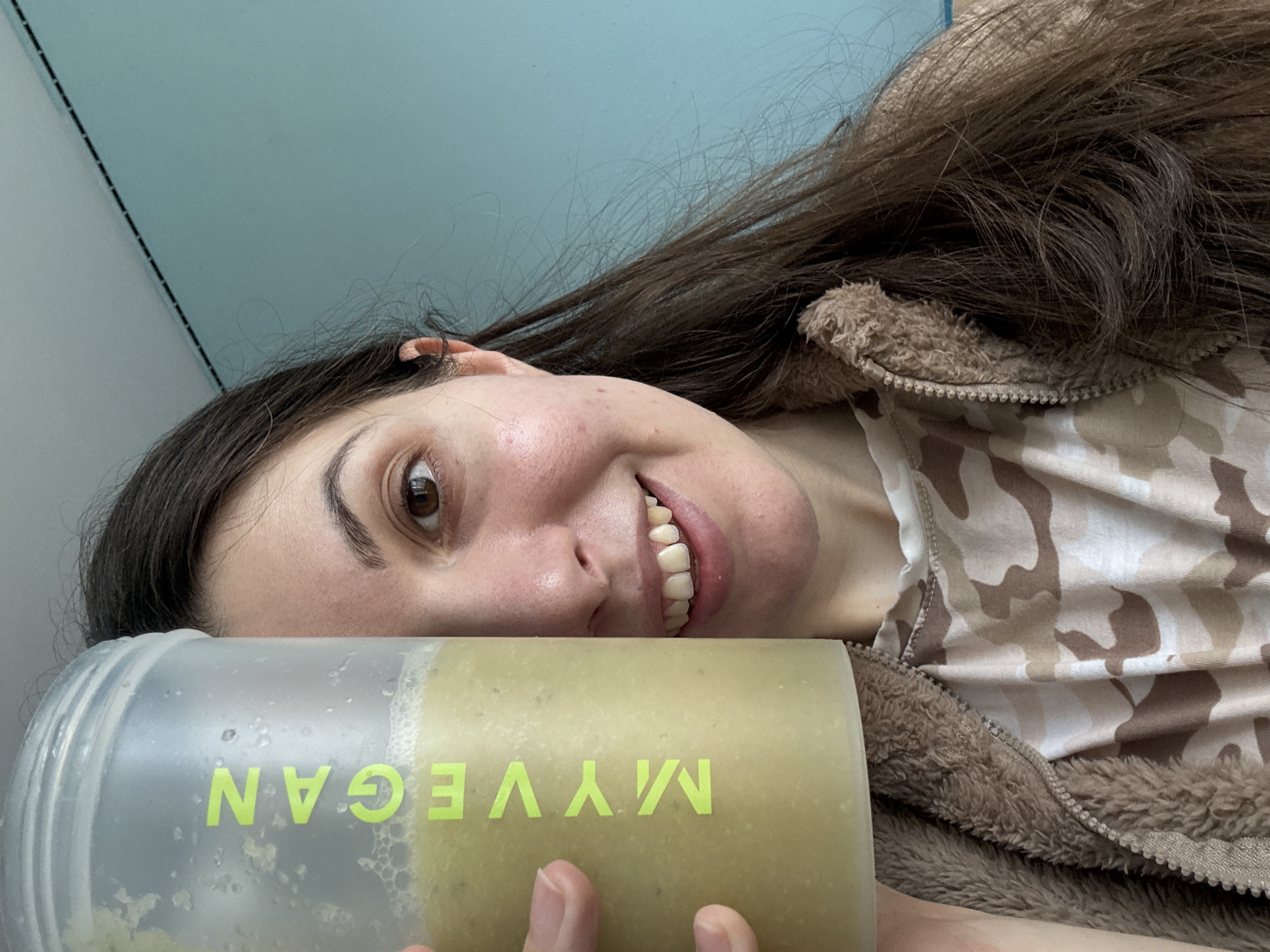 Woman displays protein shake in camouflage hoodie